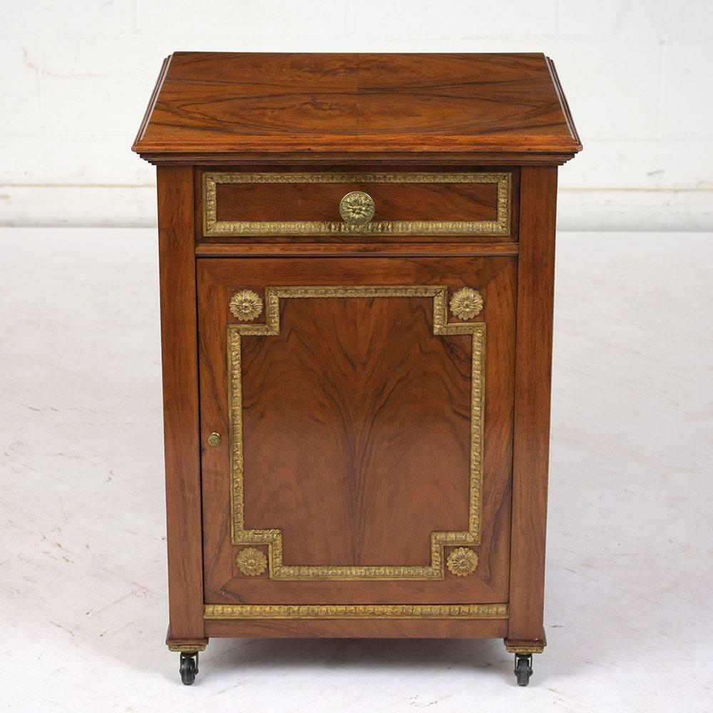 This 1890s French Louis XVI-style nightstand is cover in walnut veneers with the original finish. The drawer and cabinet door are adorned with the original brass decorative moulding with rosettes in the corners and on the knobs. Inside the cabinet