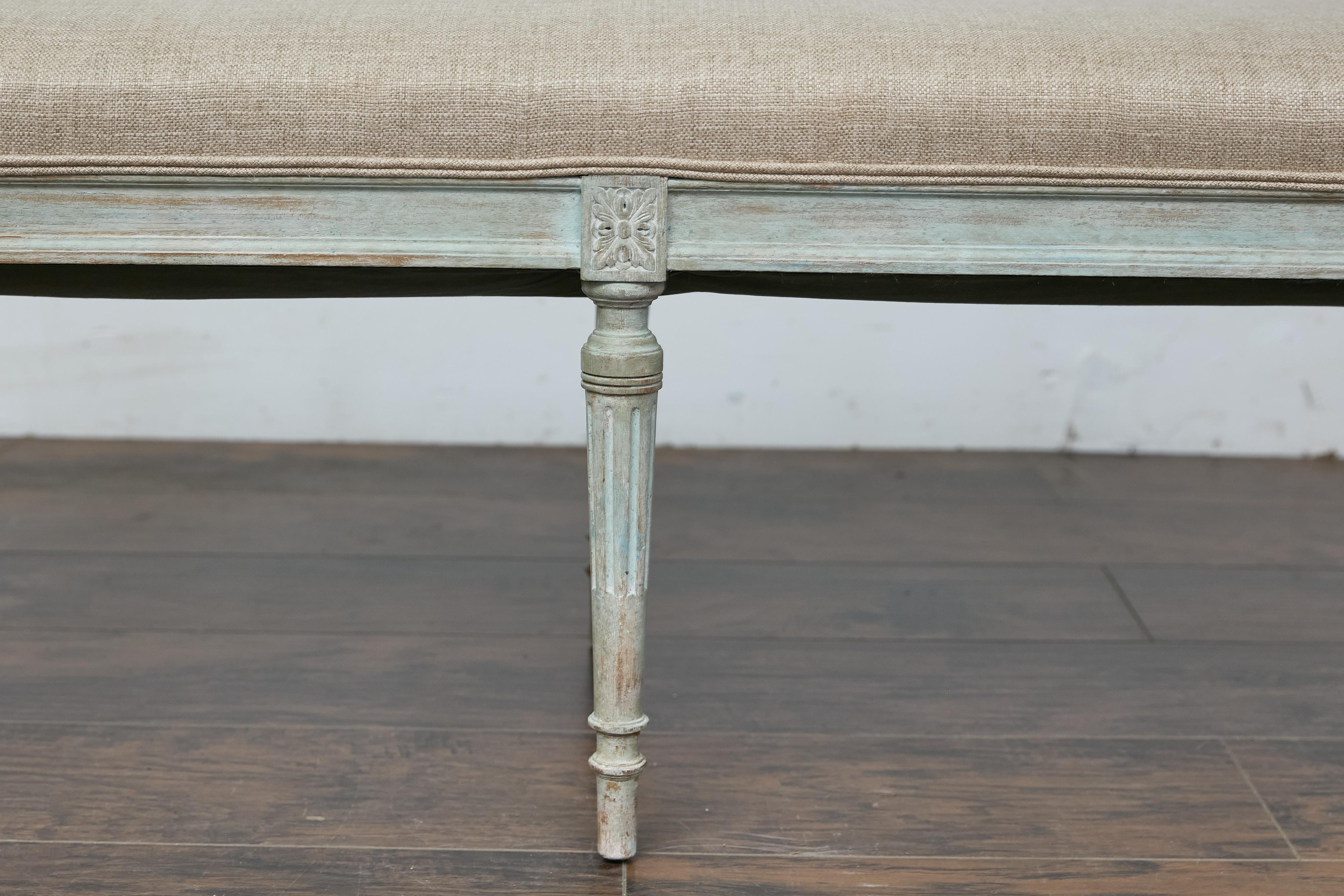 Banc en bois peint et sculpté de style Louis XVI, datant du 19e siècle, recouvert d'une tapisserie en lin. Cette élégante banquette française du XIXe siècle de style Louis XVI dégage un charme et une sophistication intemporels. Fabriqué en bois