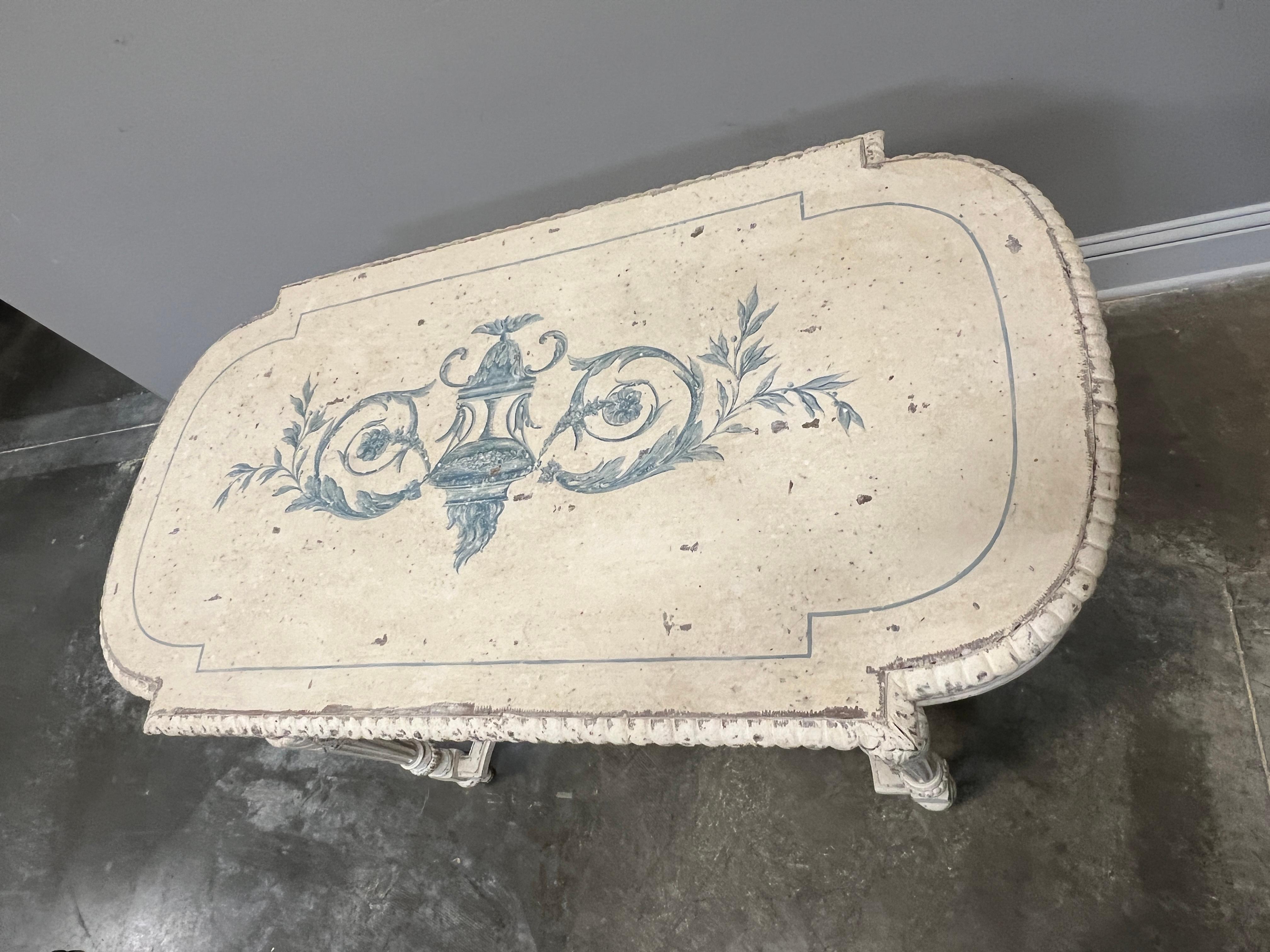Decoratively painted Victorian age parlor table in Louis XVI style. Quality construction and painted in cream with a Neoclassic motif painted on center top. Table can be used as a desk or a vanity with one drawer.

High quality construction with