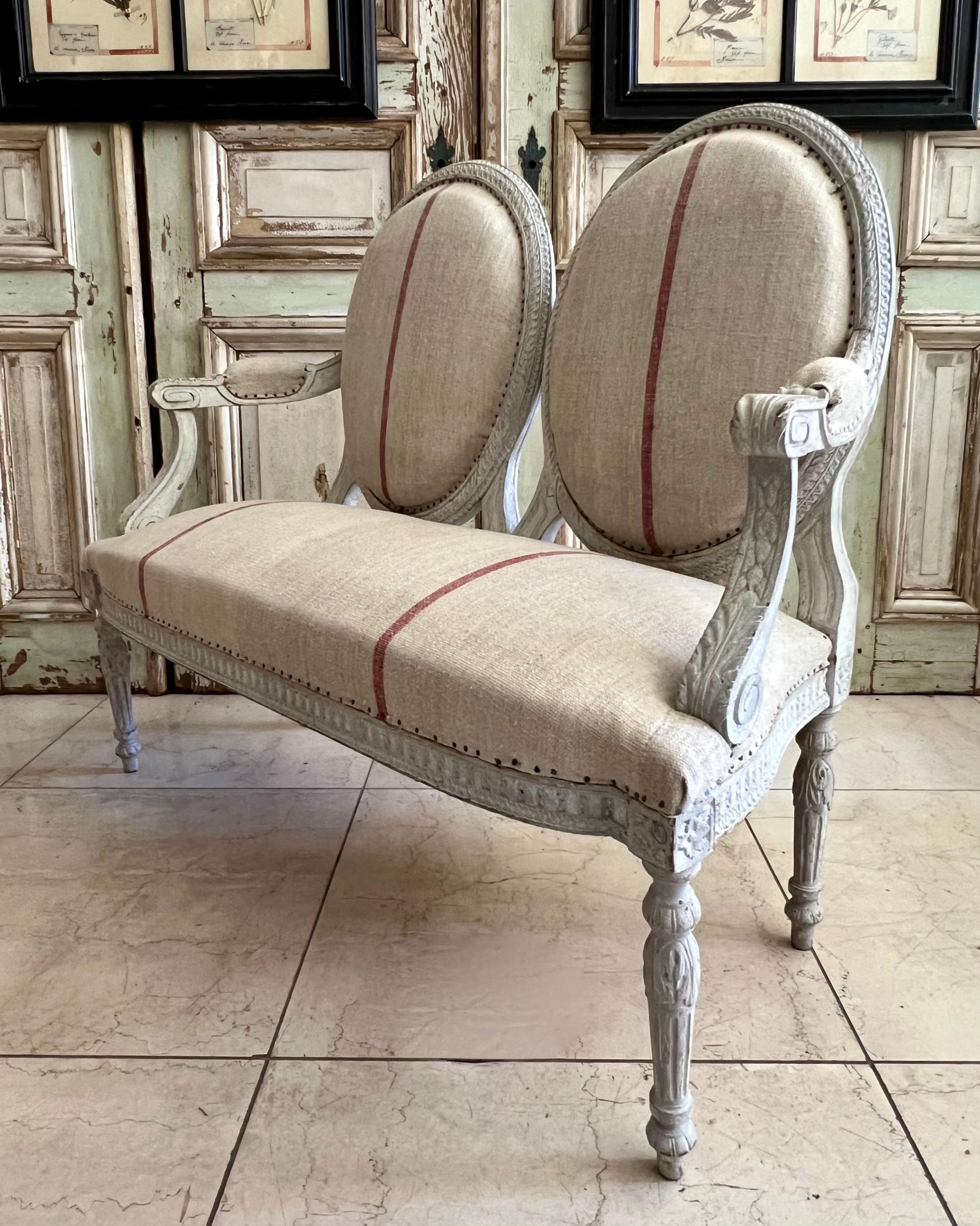 Raro divano francese del XIX secolo con doppio schienale ovale in stile Luigi XVI, con motivi riccamente intagliati, braccioli a voluta e rivestimento in lino. 
