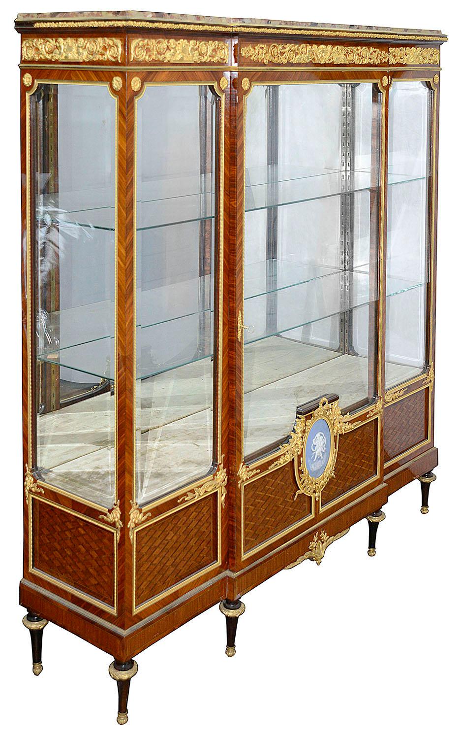 A very good quality late 19th century French break fronted marble topped Vitrine. Having wonderful classical gilded ormolu mounts and plaques with scrollingq C scrolls, foliage, Rams and putti blowing horns. Parquetry inlay to the door fronts and