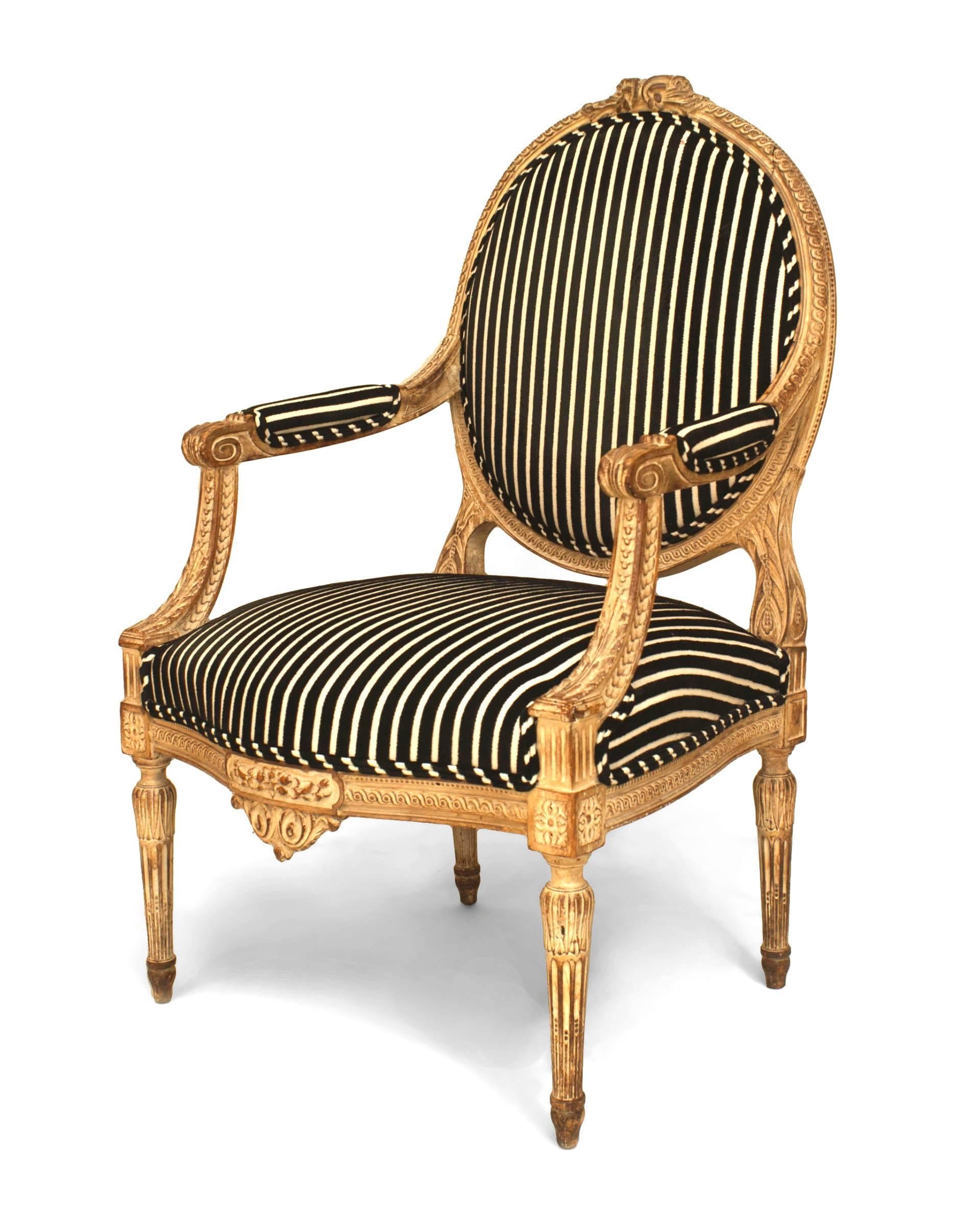 Fauteuil de style Louis XVI (19e siècle) à dossier ovale, crête sculptée et traverse avant, tapissé de rayures noires et blanches.
