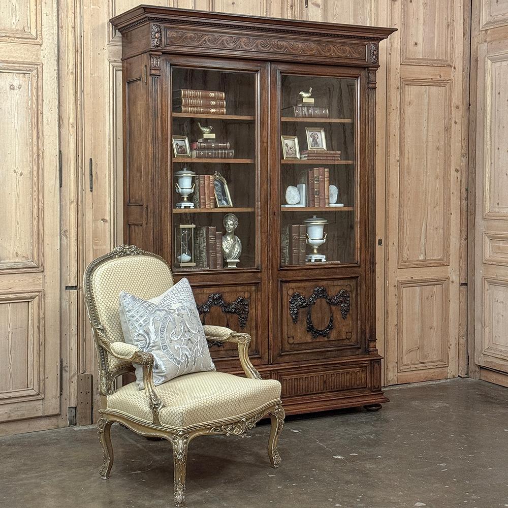 la bibliothèque Louis XVI en noyer du 19ème siècle est une expression majestueuse du style classique qui défie véritablement le temps Une couronne à plusieurs niveaux surplombe le capot sculpté d'une vague grecque flanquée de rosettes