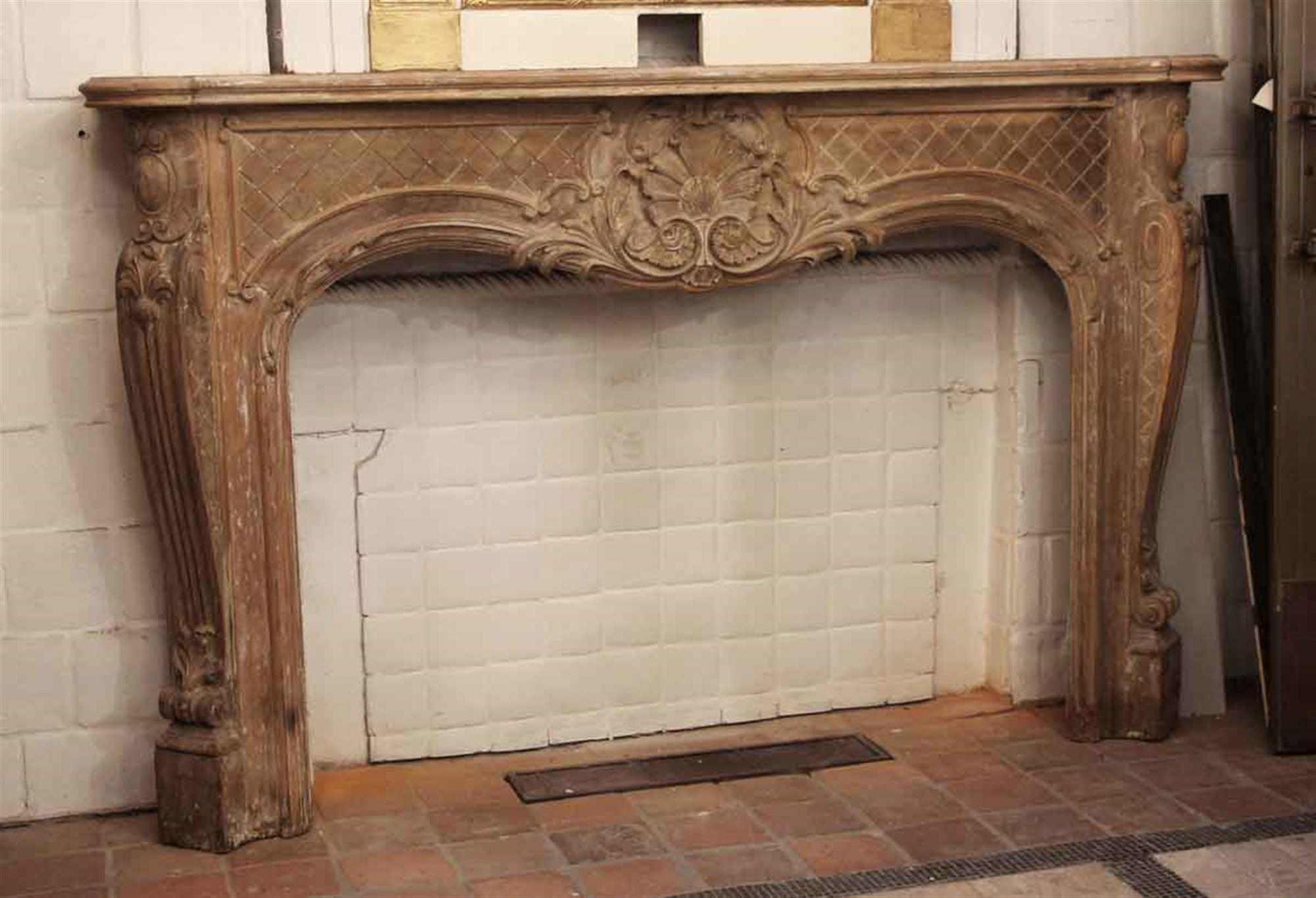 Large scale 19th century hand carved wooden mantel in the Louis XV style. Breast of mantel has carved lattice pattern and a centerpiece with shell floral and acanthus leaf detail. Fluted pilasters grace the sides with top mounted protruding ovals.