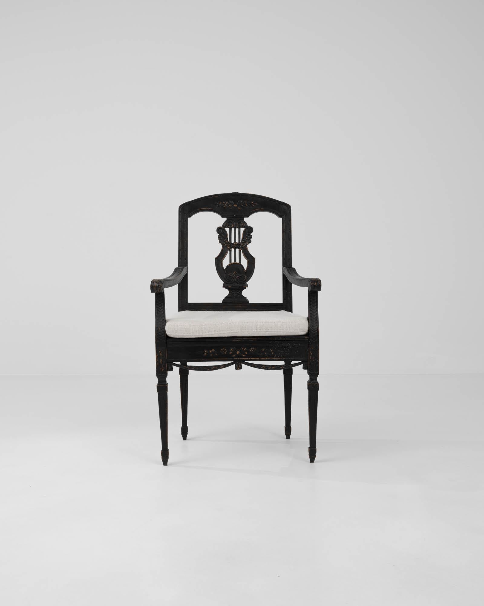 A carved wooden side chair made in 19th Century France. The black patina of this chair contrasts with the reupholstered white upholstery of the seat.
Intricate carved details define the style: tapered feet with fluted legs; rosettes,and carved