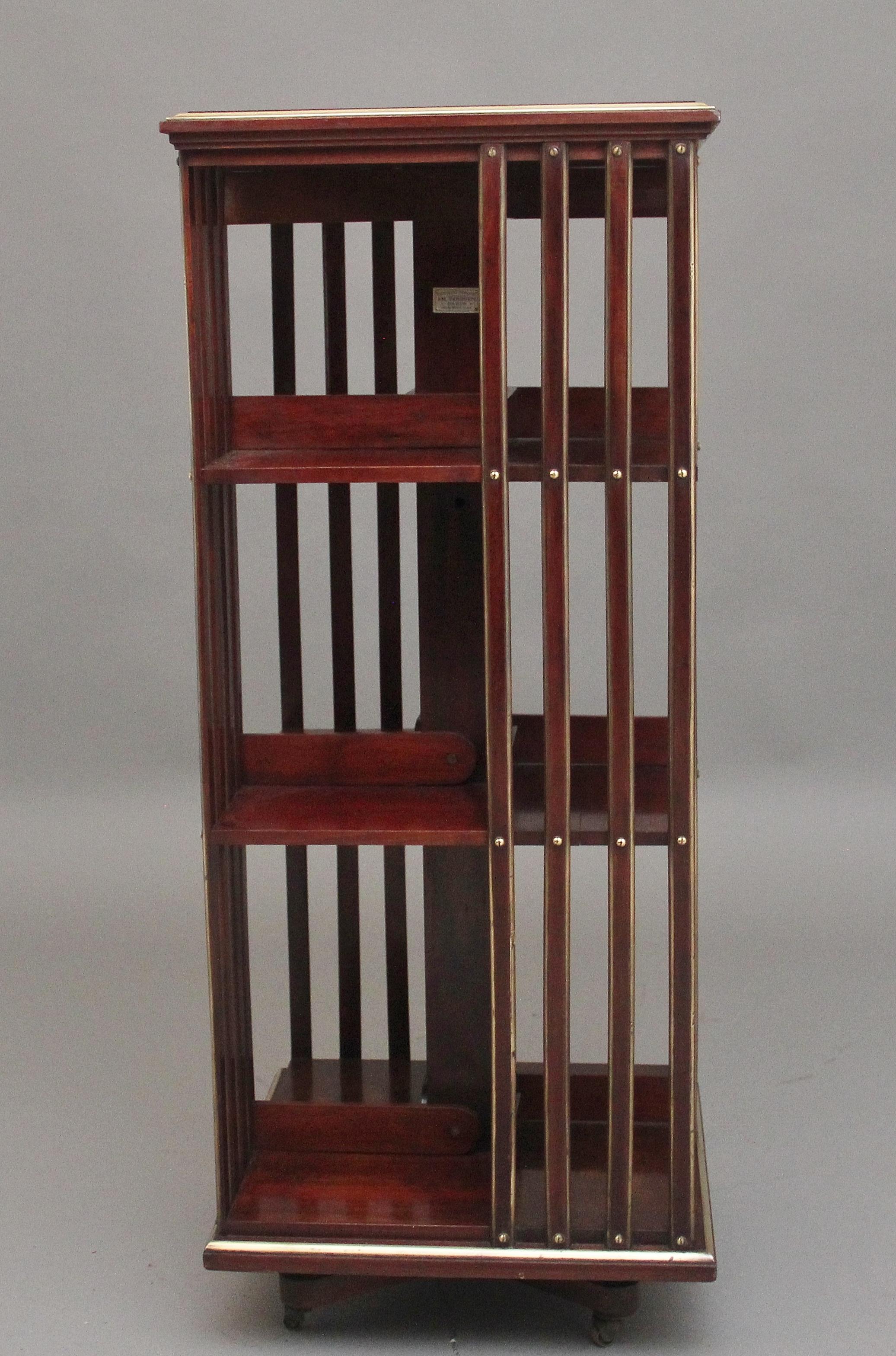 19th Century French mahogany and brass revolving bookcase, having a nice figured top with brass moulding around the edge, the bookcase having three shelves with each shelf split into four sections, having mahogany and brass dividers, supported on a
