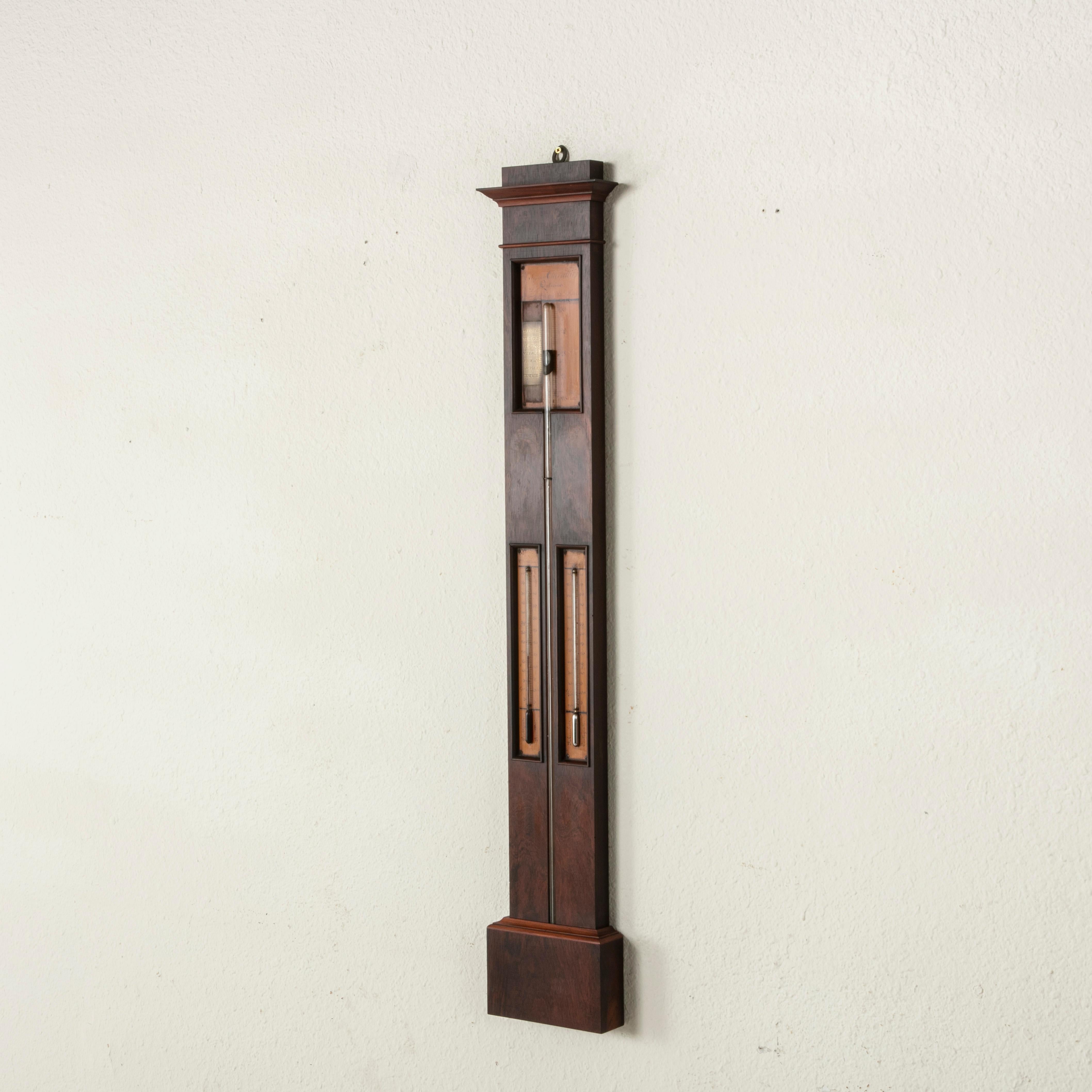 This 19th century French mahogany barometer features its three original glass tubes, two thermometers, and one central barometer. An inlaid lemonwood panel at the top is signed L'ingenieur Chevallier, Opticien, the name of the maker Chevallier