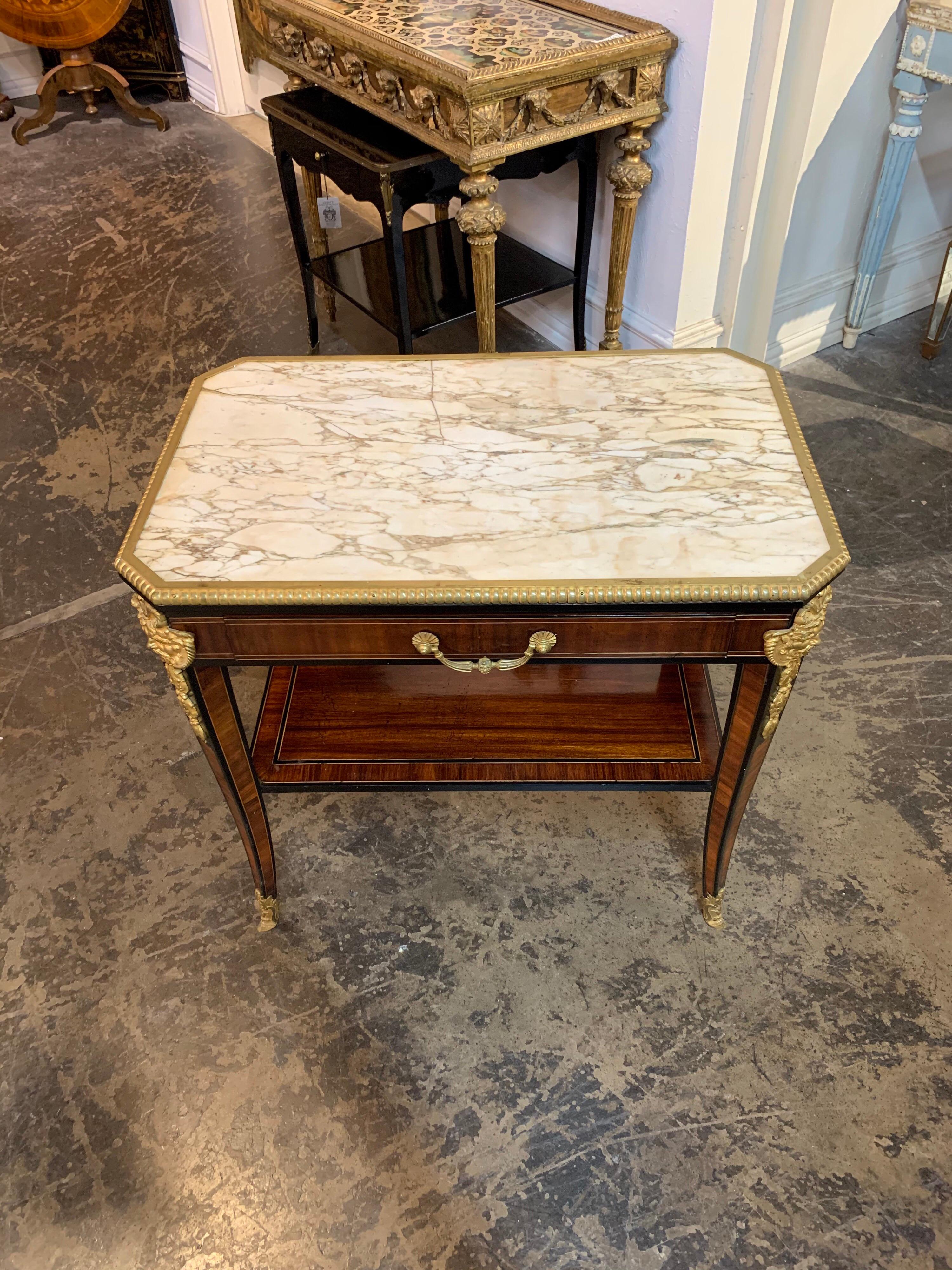 Exquisite 19th century French mahogany and ormolu table with inset marble top. Fine decorative details including a face on the outer edges of the table. The piece also has a bottom shelf and one drawer for storage. Makes an impressive statement!