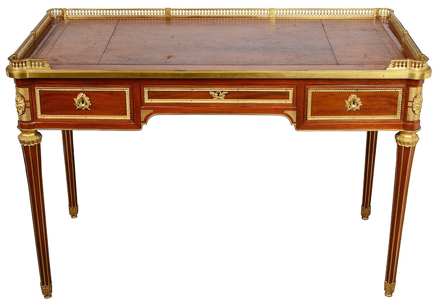 A fine quality late 19th century French Mahogany Bureau plat, after Henry Dasson, having an inset leather top with a three quarter ormolu gallery, three Mahogany line freize drawers, each with gilded ormolu ring drop handles, ormolu moldings to the