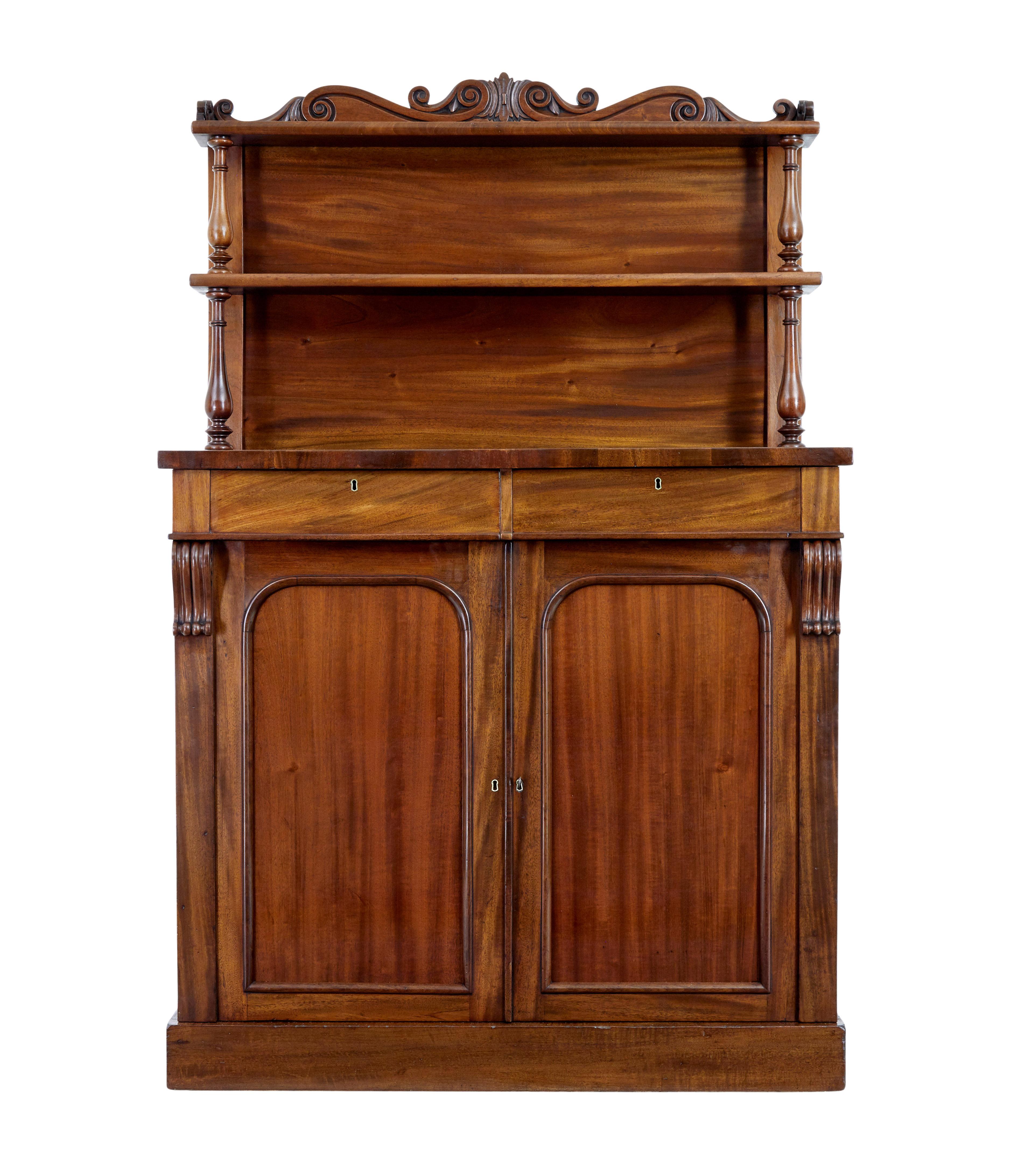 Credenza a chiffoniera in mogano del XIX secolo, circa 1870.

Credenza di buona qualità realizzata in ricco mogano. Parte superiore con galleria a volute intagliate e 2 ripiani sostenuti da supporti torniti. 2 cassetti sotto la superficie superiore,