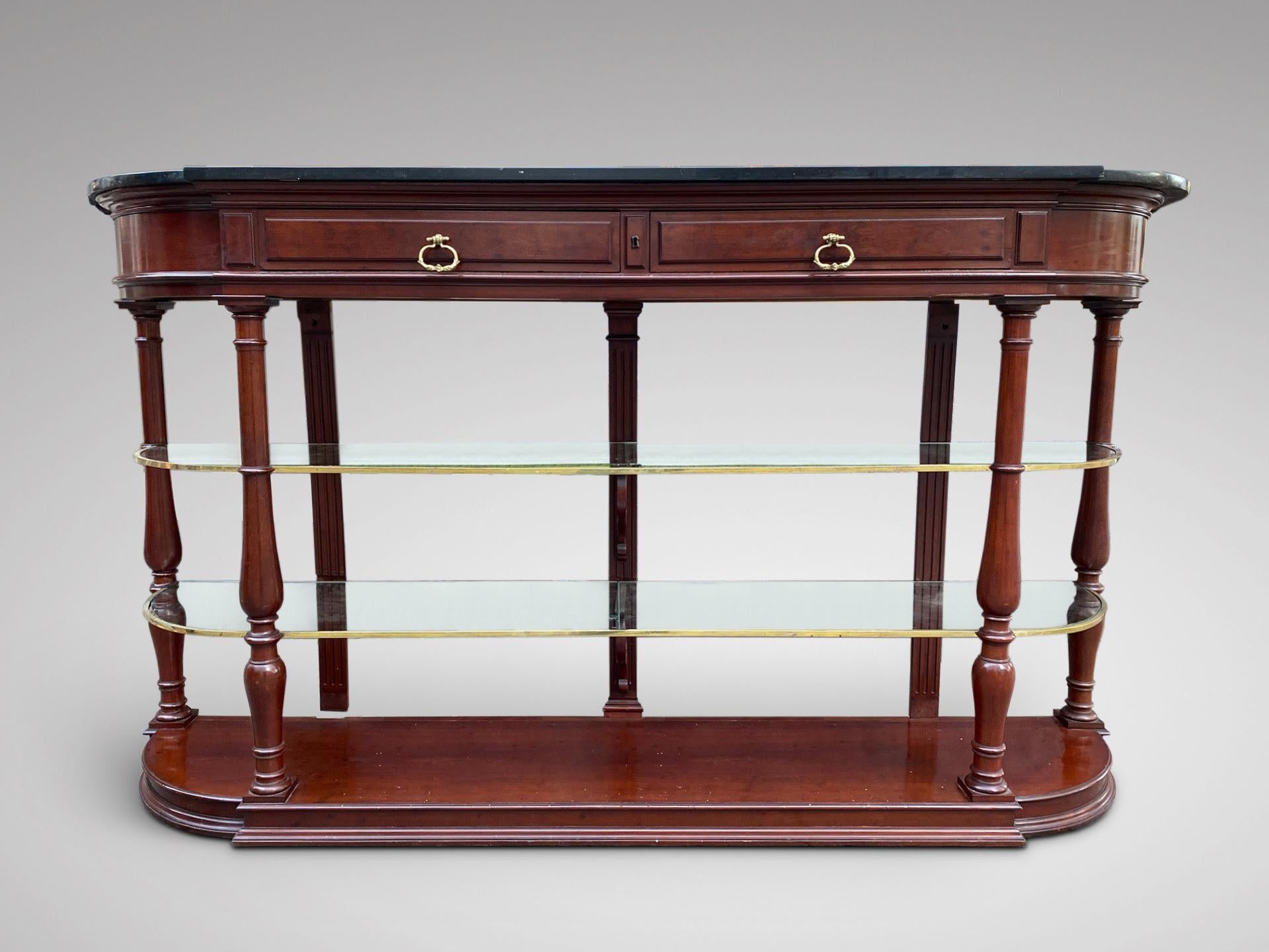 We are delighted to offer for sale this 19th century French mahogany console table with shaped black marble top above a pair of drawers with working lock, two glass shelves with brass fittings, supported by four turned supports, all standing on a