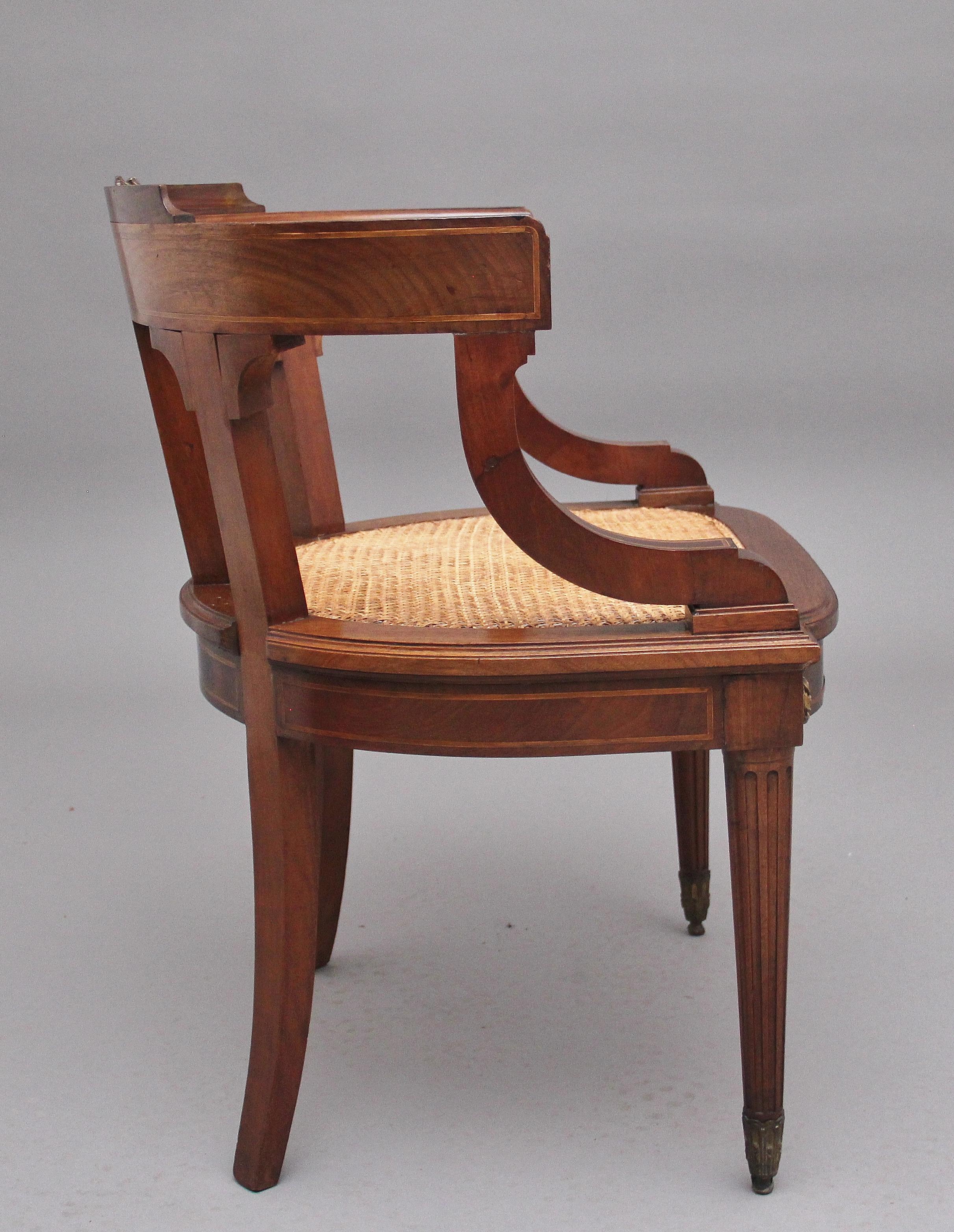 An elegant and decorative 19th Century French mahogany desk chair with a cane seat, having a curved back with fluted central splat back, curved and inlaid arms, inlaid frame with decorative circular patraes, standing on front turned and fluted legs