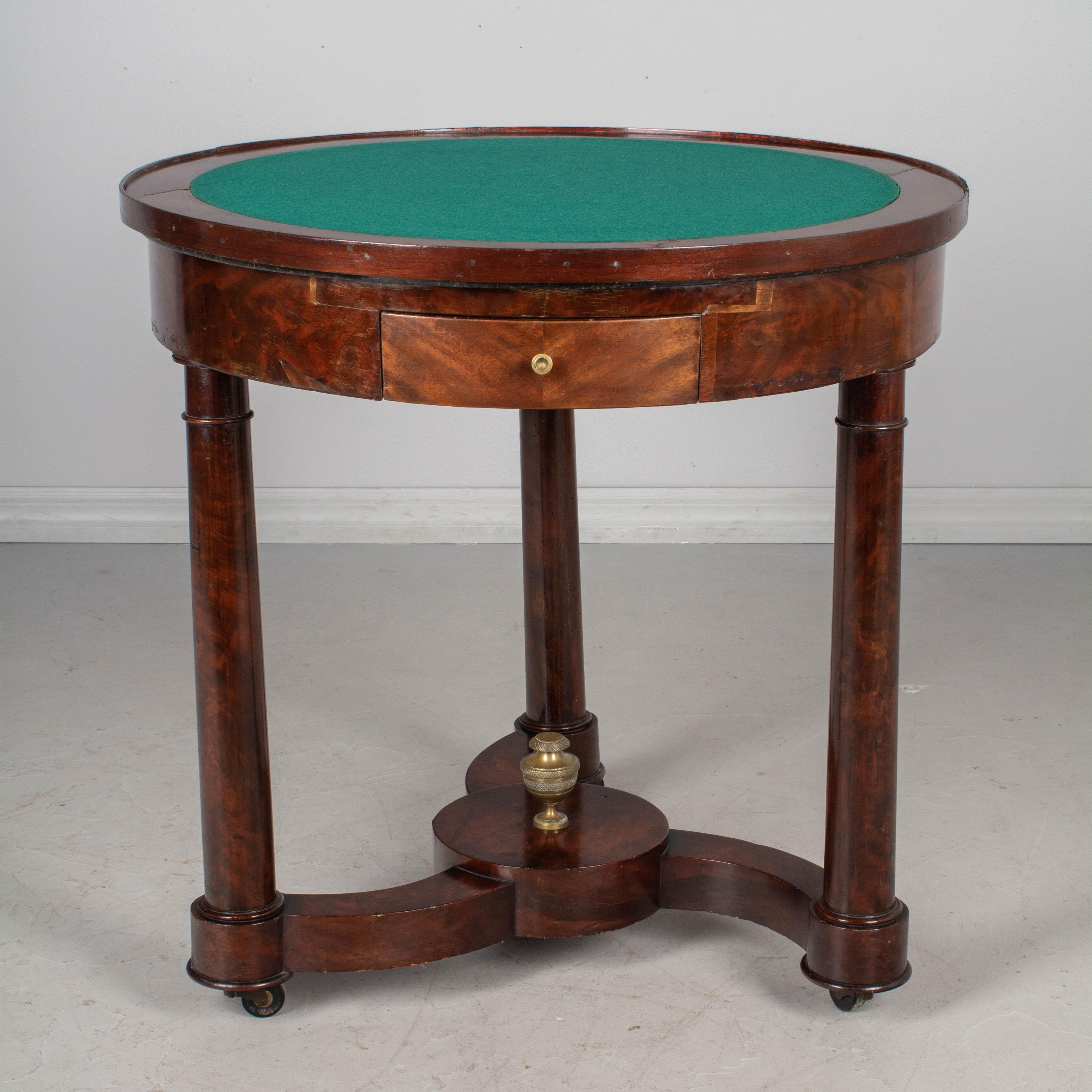 A 19th century French Empire Period mahogany gueridon, or game table, with Grey St. Anne marble top. A versatile table with removeable top, one side with green felt and the other with black leather. Veneer of mahogany banding around the top.