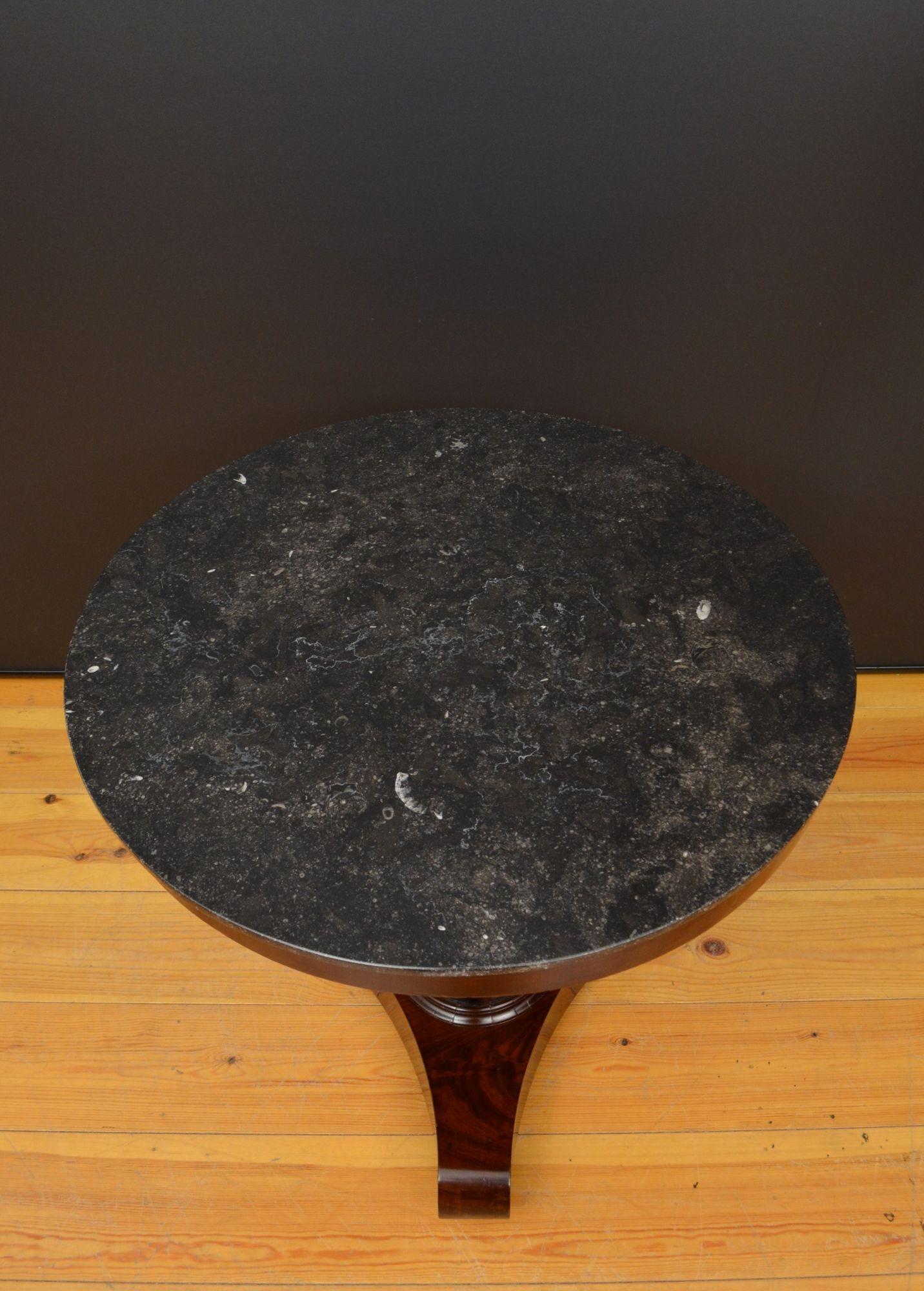 J039 Table de guéridon en acajou flammé français du 19e siècle avec plateau en marbre fossilisé noir d'origine. Assis sur une frise en acajou, avec une colonne centrale en acajou flammé et une base tripode. Terminaison par des roulettes en laiton