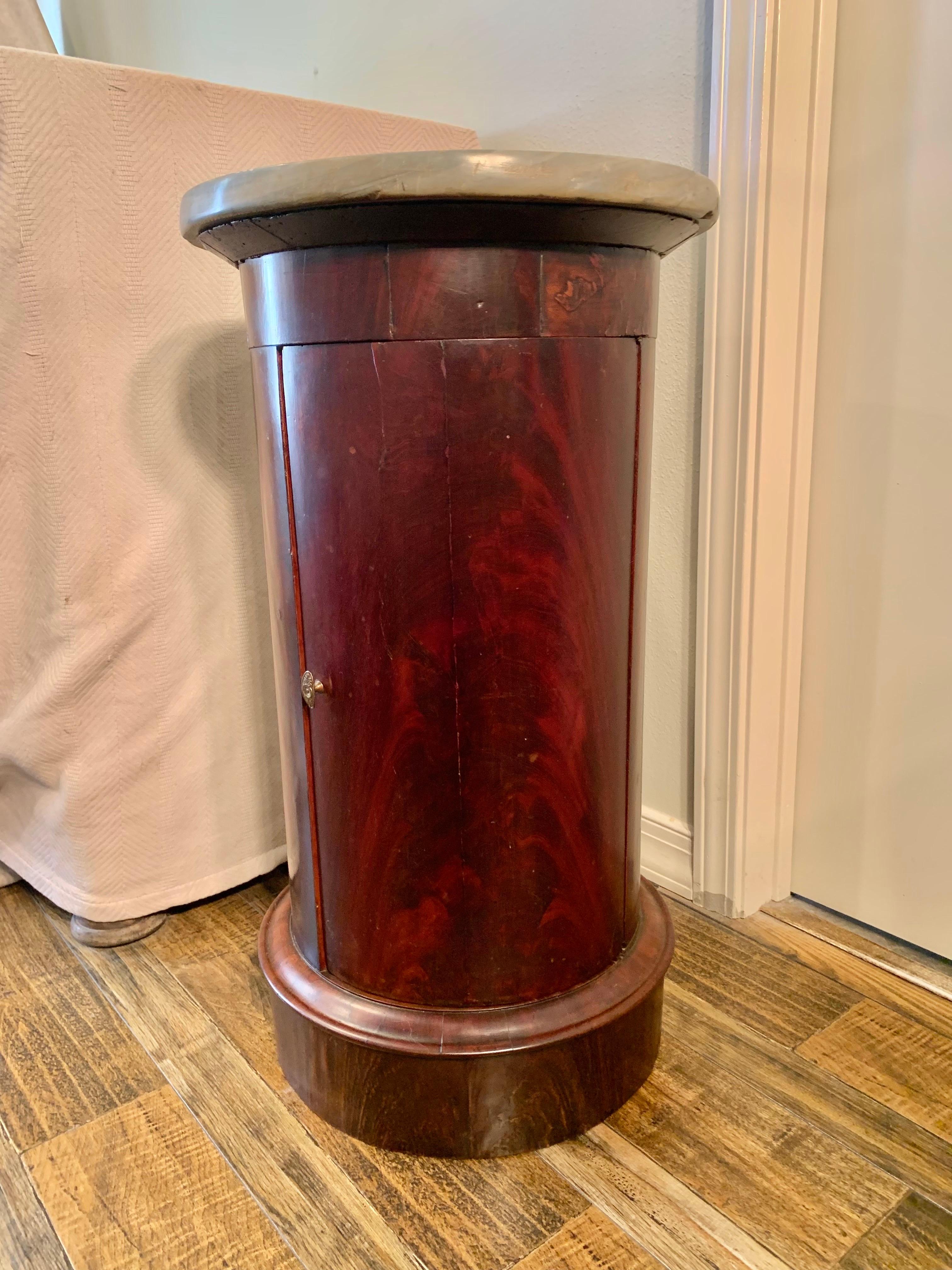 Found in the South of France this 19th Century French mahogany marble top somno or drum table features a hinged curved door with brass pull. The door opens to reveal two shelves. The cylindrical form and clean lines of the piece lend a refined yet