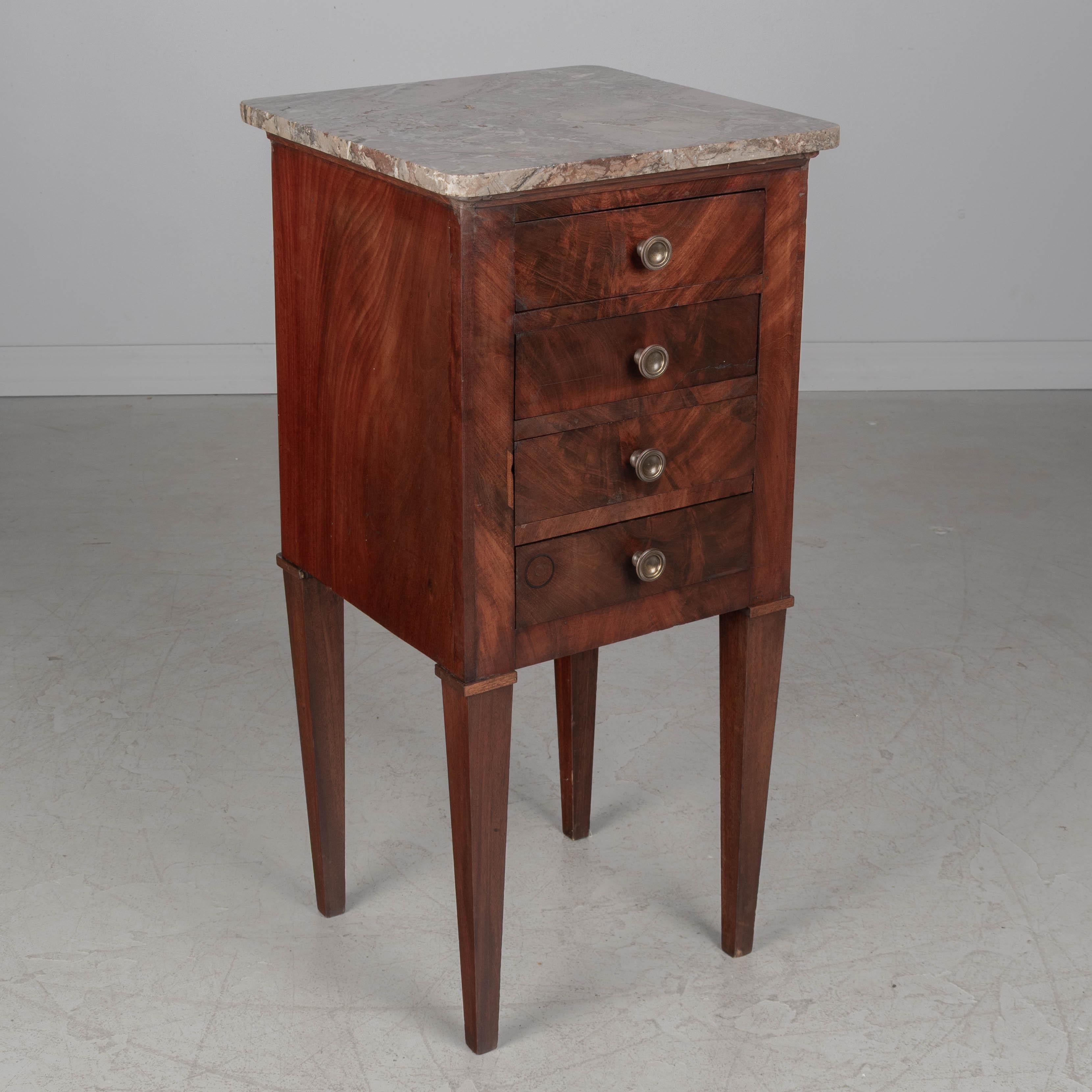 An early 19th century French marble top side table, handcrafted of solid and veneers of mahogany and finished on all four sides. Four dovetailed drawers with brass knobs. Sturdy tapered legs. Pegged construction. Oak as a secondary wood. Good