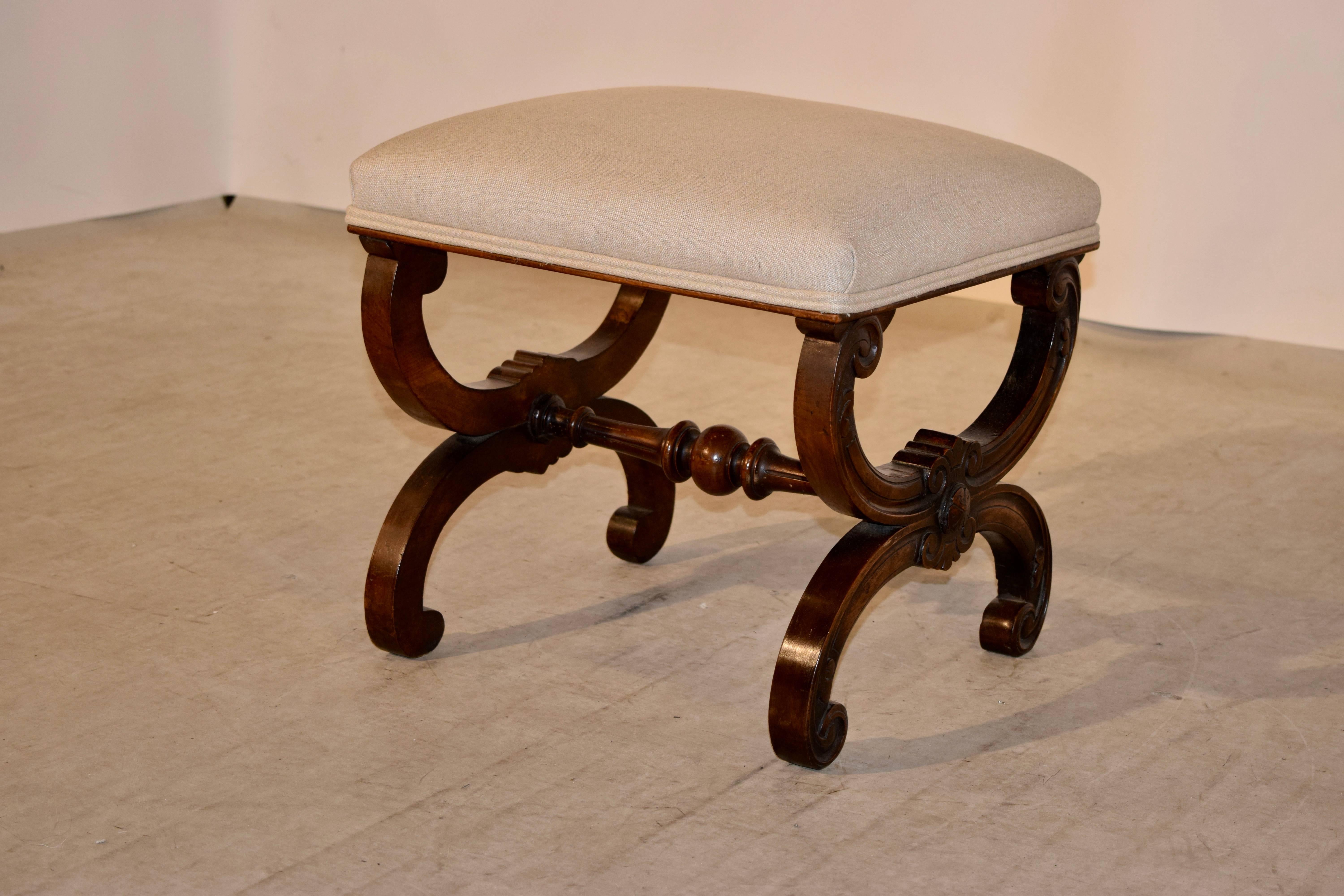 19th century French stool made from mahogany with a newly upholstered top in linen which has a double welt trim around the seat. The legs are fancy X-stretchers, connected by a hand turned stretcher.