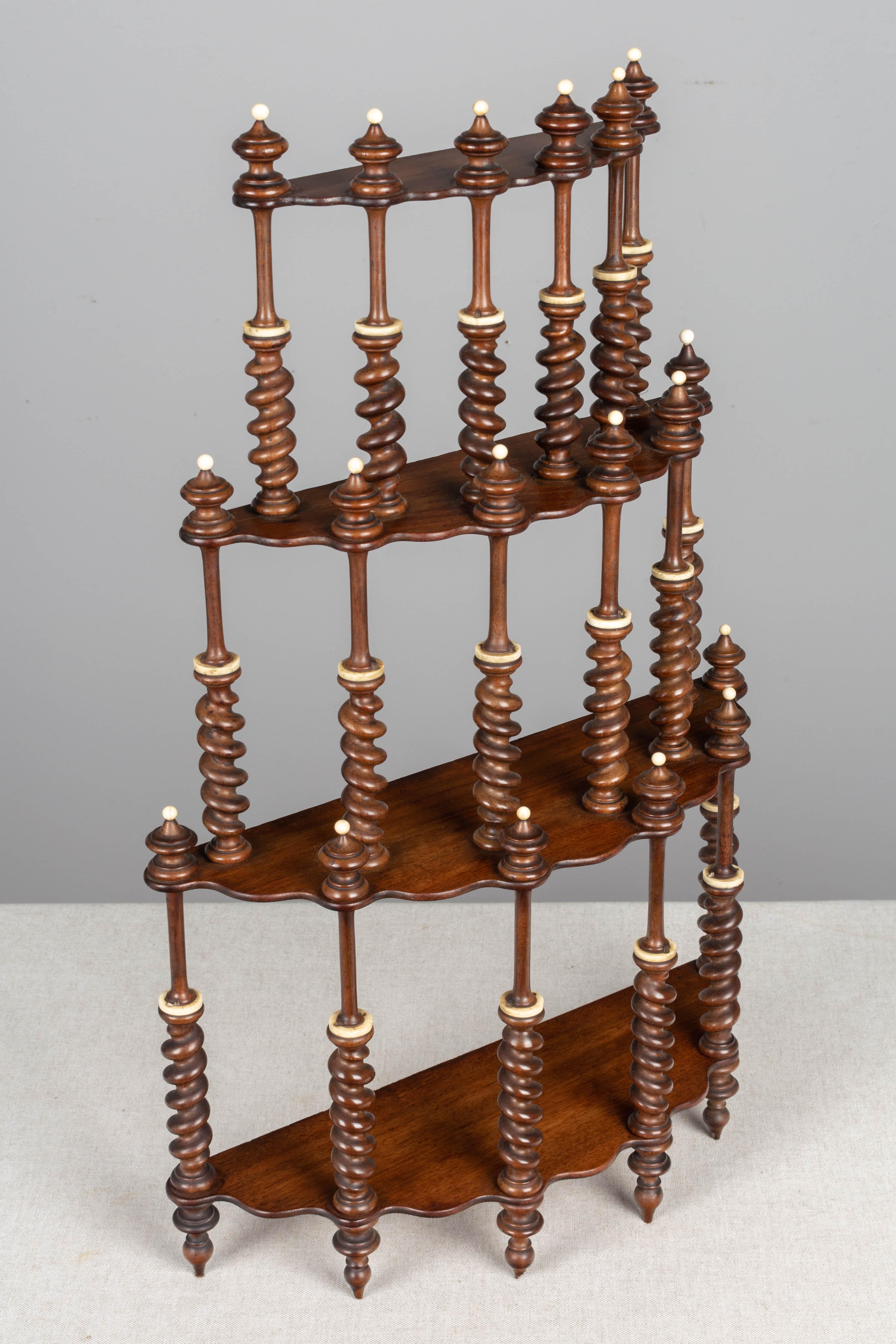 A 19th century French mahogany shelf with four demilune tiers connected by delicate turned barley twist spindles with decorative finials. Skillfully crafted, this interesting decorative tabletop folly is likely the work of an ebonite apprentice.