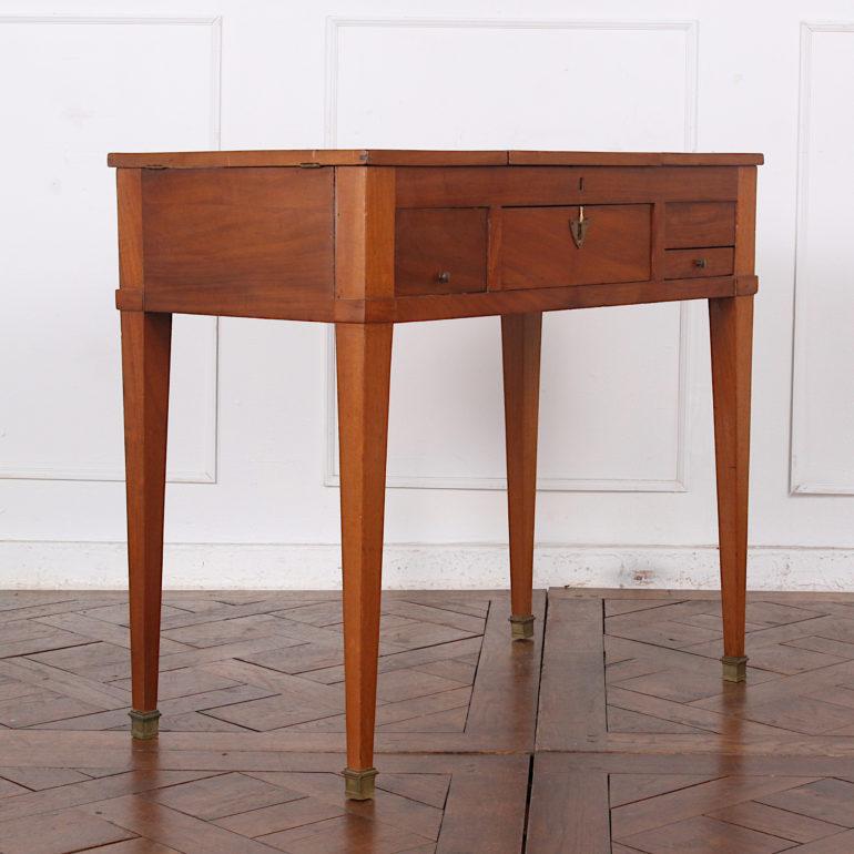 Simple French Directoire style mahogany vanity or desk, the top with central fold-open mirror and two opening side compartments. Two drawers fitted in the front. Elegant square tapering legs with brass capped feet.