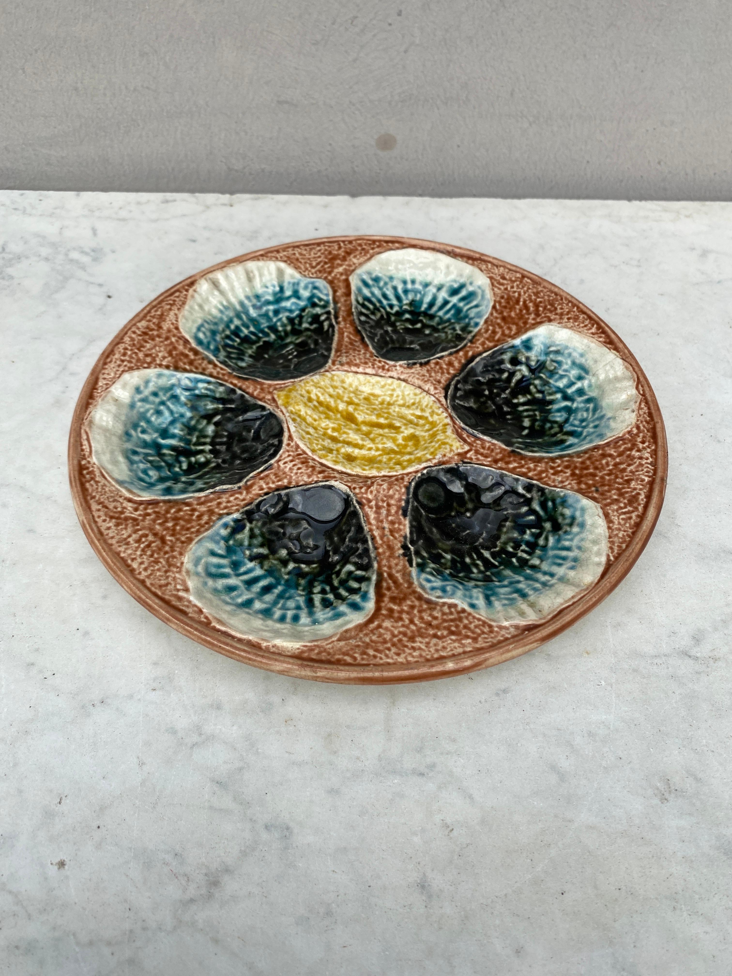 Plato de ostra de mayólica francesa del siglo XIX sin firmar, con un limón en el centro.