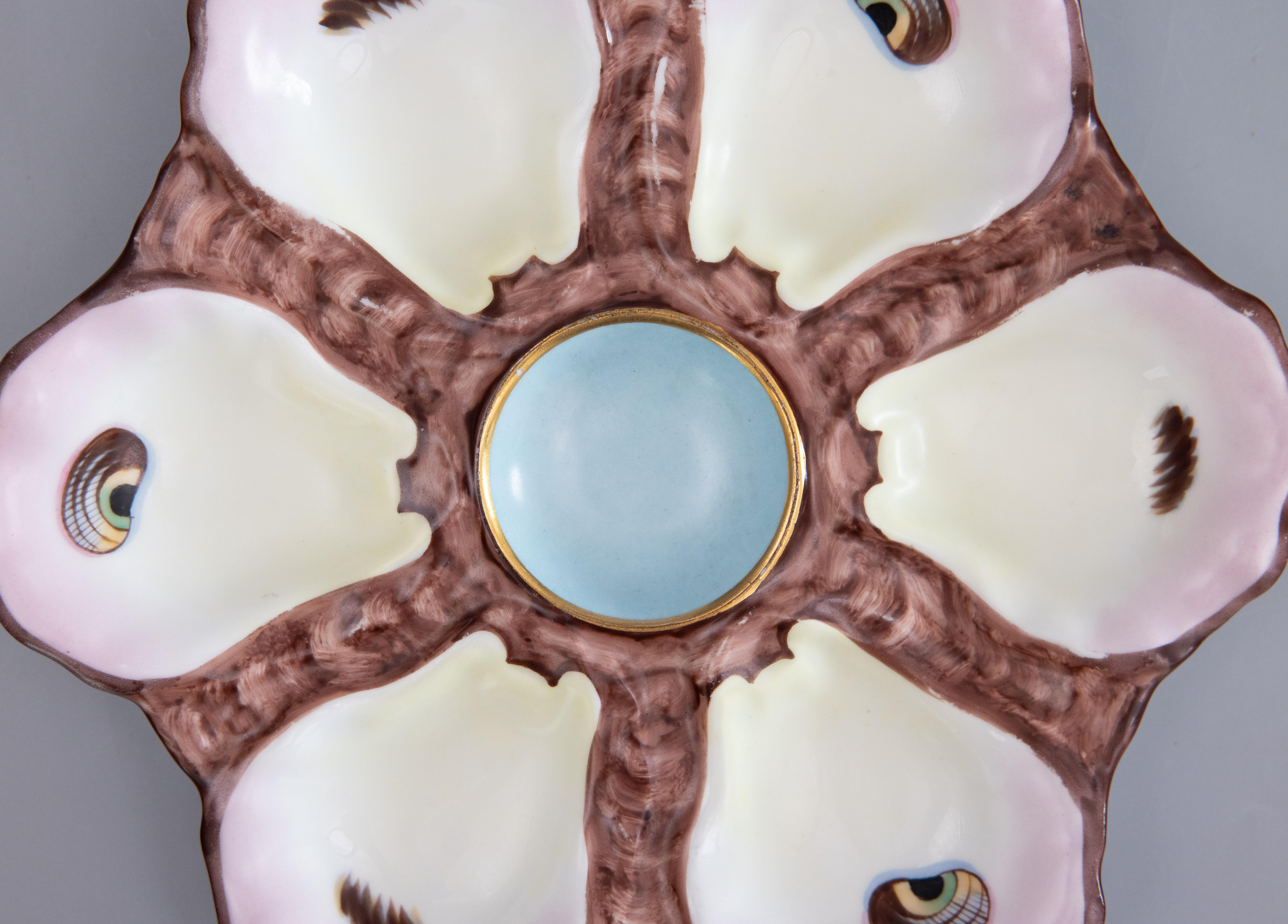 A gorgeous antique 19th-Century French majolica porcelain oyster plate. This fine quality oyster plate has six wells with hand painted 'eyes,' a soft blush pink tint on the edges, and a lovely robin egg blue center. It displays beautifully and would