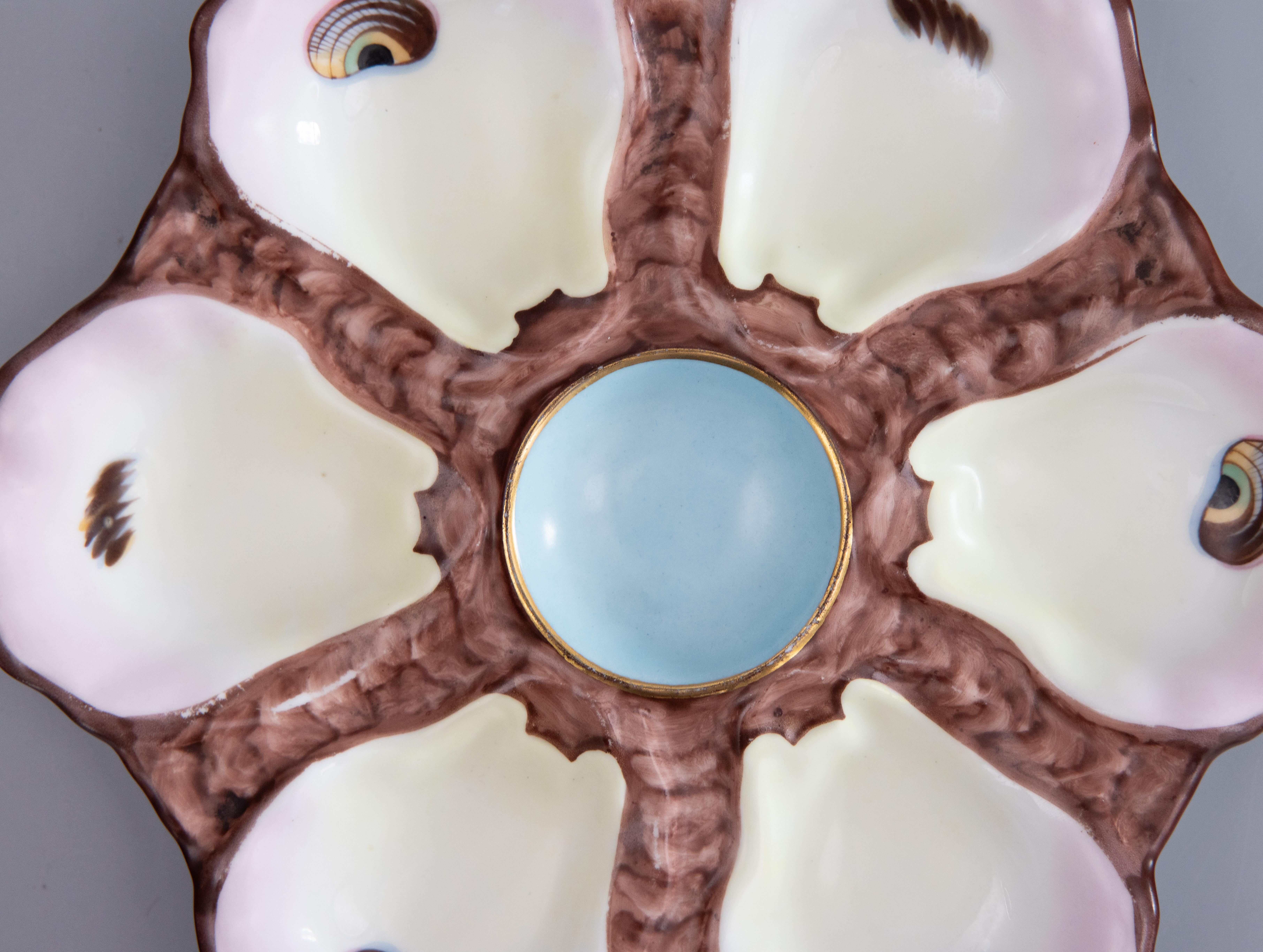 A gorgeous antique 19th-Century French majolica porcelain oyster plate. This fine quality oyster plate has six wells with hand painted 'eyes,' a soft blush pink tint on the edges, and a lovely robin egg blue center. It displays beautifully and would