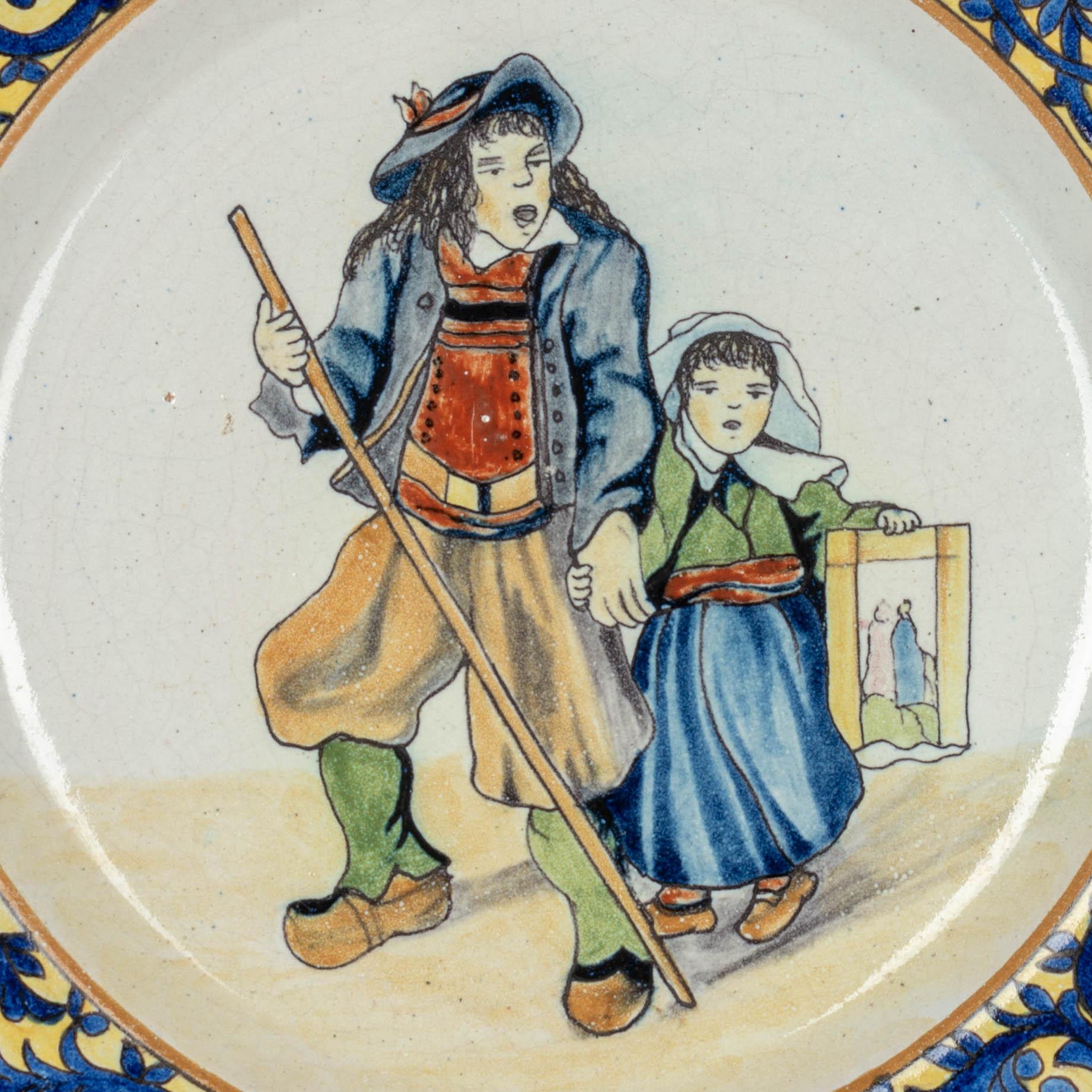 Pate en faïence de Malicorne de la fin du XIXe siècle, peinte à la main d'un homme et d'un enfant bretons en costume traditionnel et d'une bordure décorative bleue et jaune sur le bord. Belle qualité, plaque épaisse. En très bon état, avec seulement
