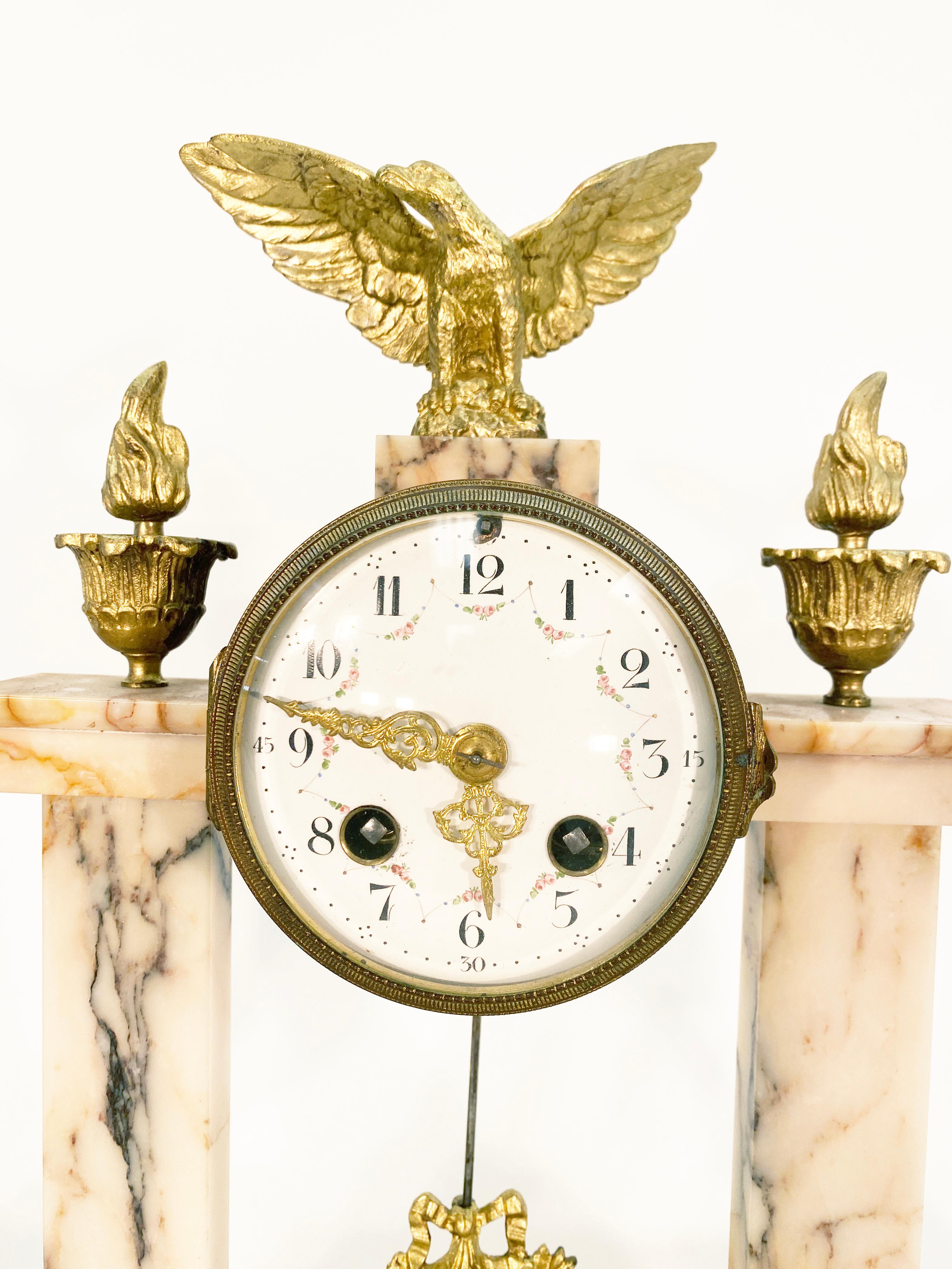 French marble and bronze gilt three piece garniture clock. Clock features marble columns supporting the central clock. Enamel faced and hand painted dial bronze gilt details in the feet, pendulum, min and hour hands with eye catching details of