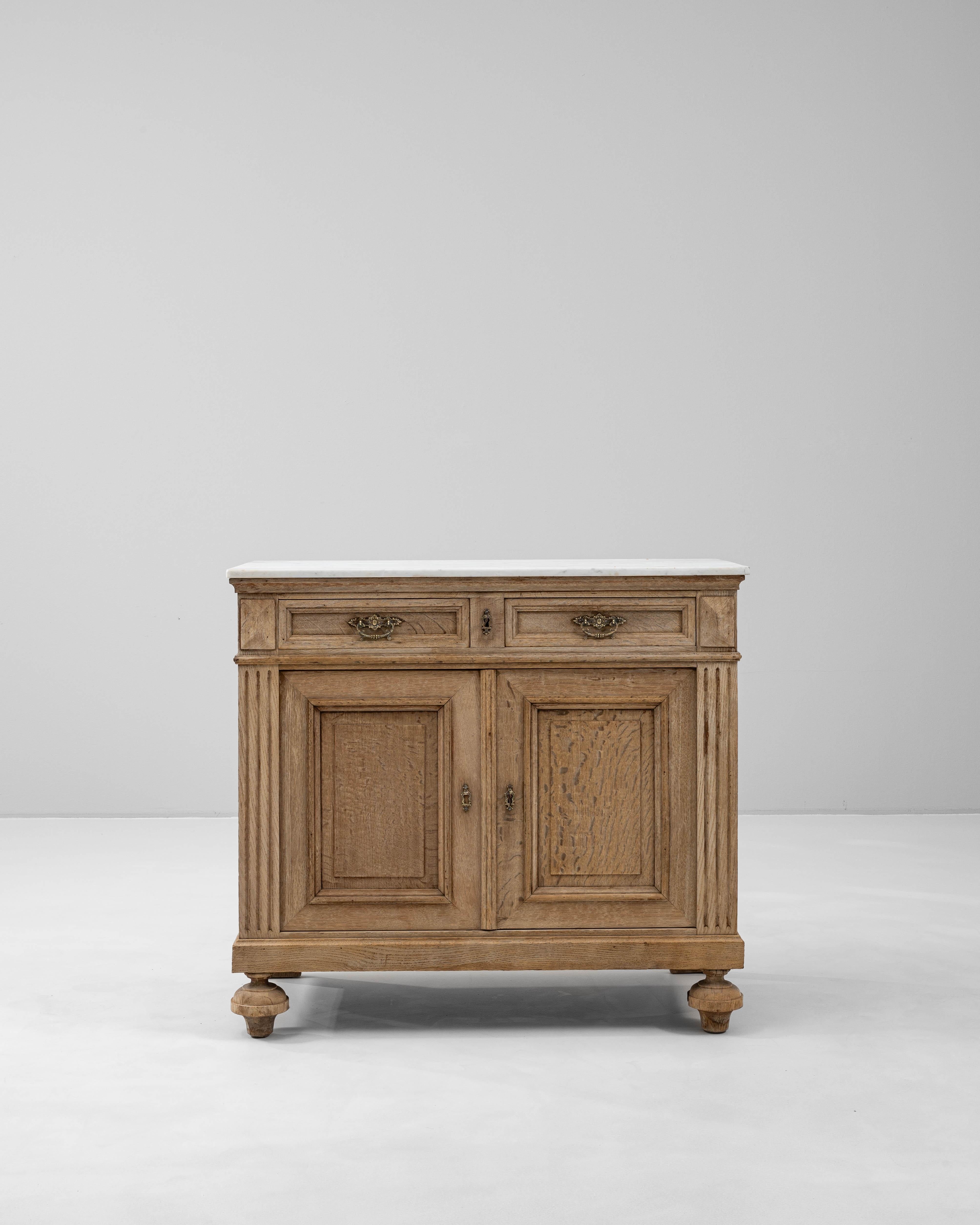 Questo buffet francese del XIX secolo con piano in marmo presenta una classica silhouette provinciale arricchita da sottili dettagli architettonici e da una patina calda e naturale. Il corpo rettangolare è realizzato in rovere massiccio e presenta