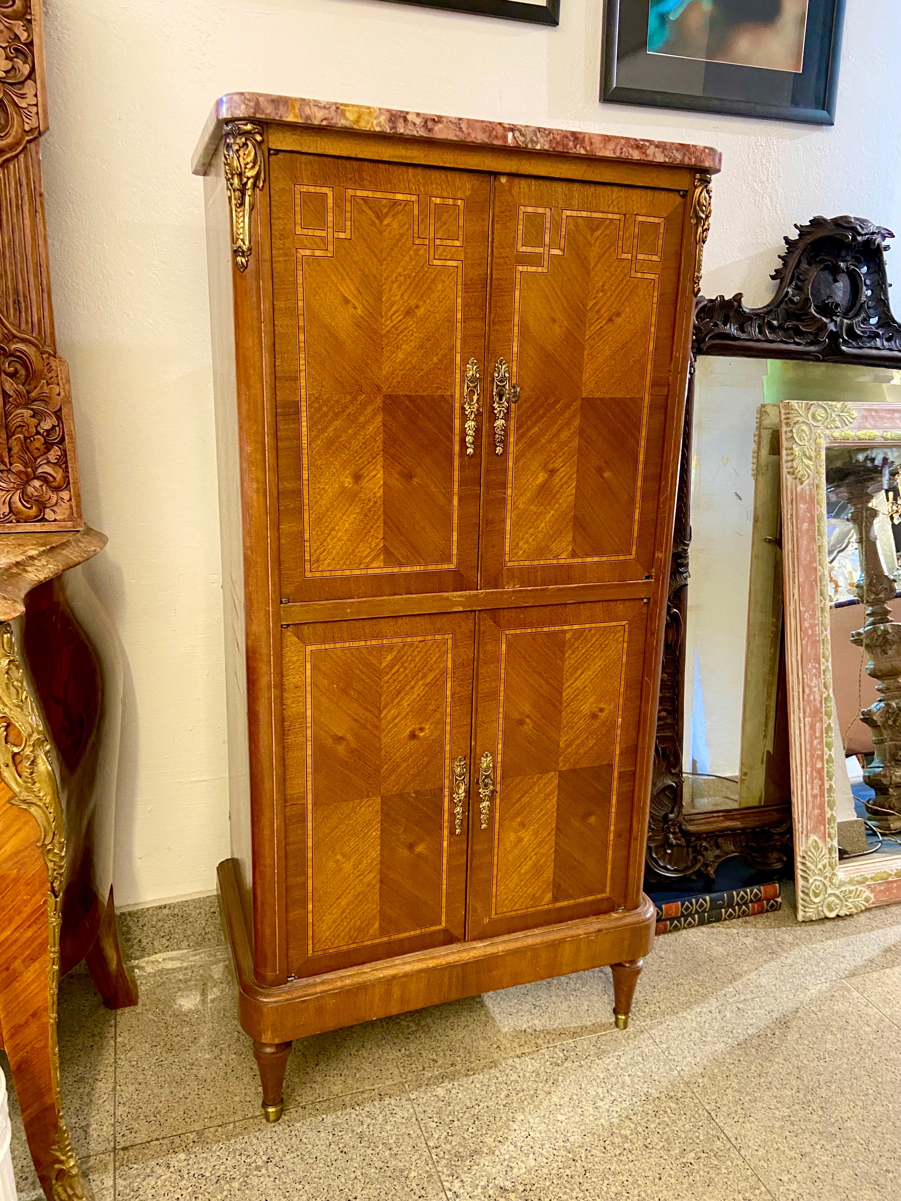 19th Century French mahogany cabinet in Louis XVI style with geometric patterns on both front and sides. The top surface is made of rose marble and there are two compartments each one with two doors and original keys. Could be used as a dry bar as