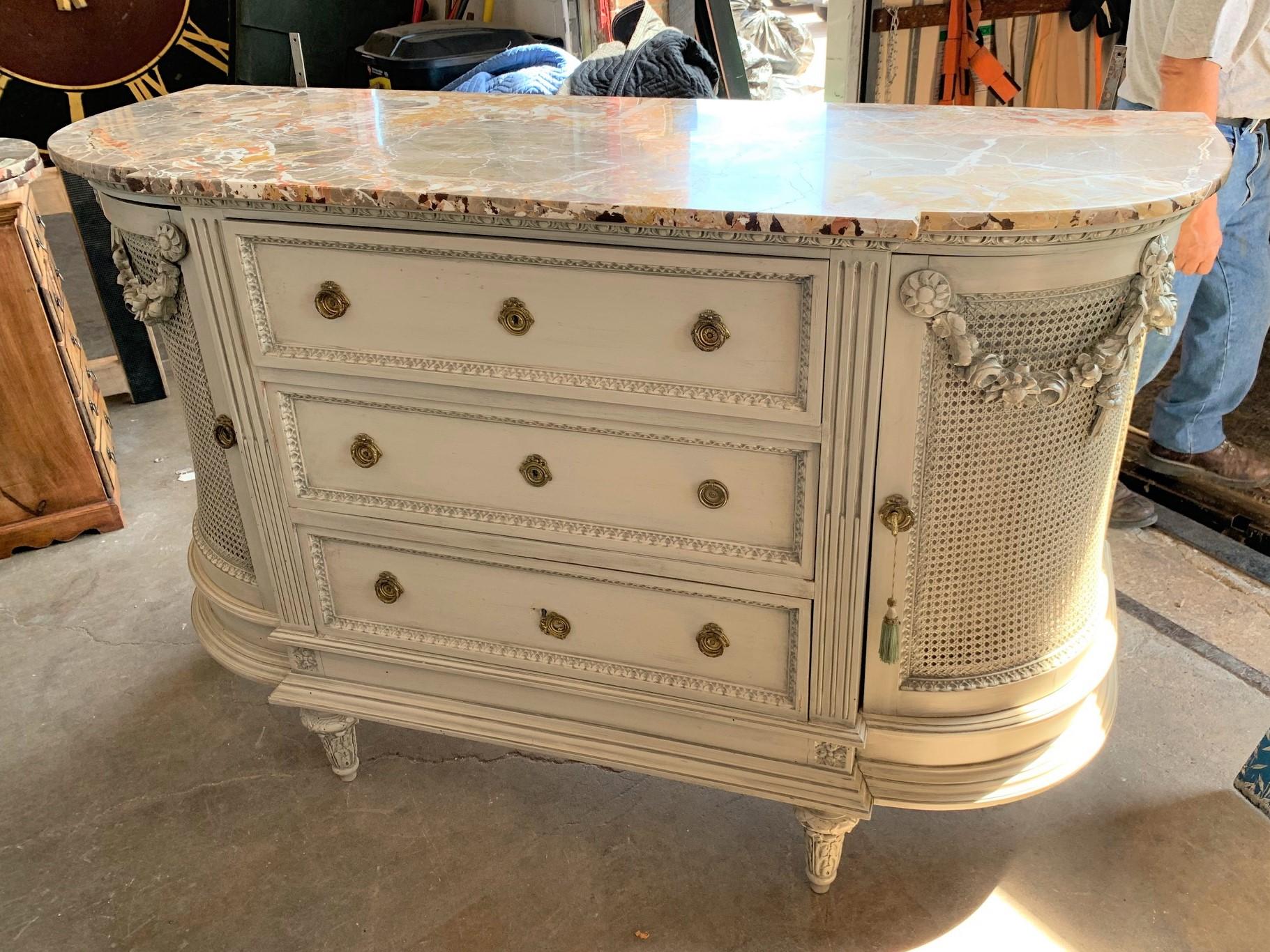 Lovely 19th century French Louis XVI style sideboard or buffet with a painted finish and a remarkable breccia marble top. The curved cupboards with caned panels and carved festoon swags. Fitted with three drawers with bead trim, and raised on short