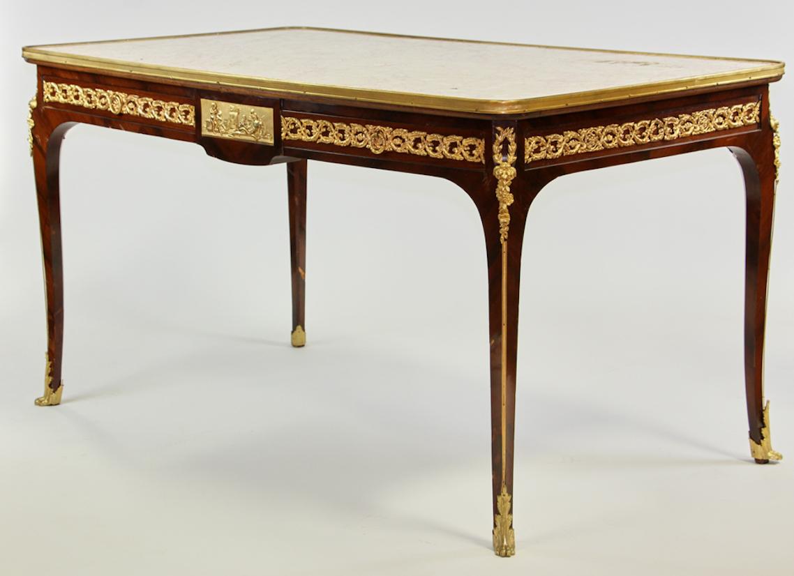 !9th century French Belle Epoque writing table with gilt ormolu mounts on the feet corners and apron. The top is a single rose and cream-colored marble slab with wonderful veining. The marble top has a gilt bronze band around the entire perimeter of