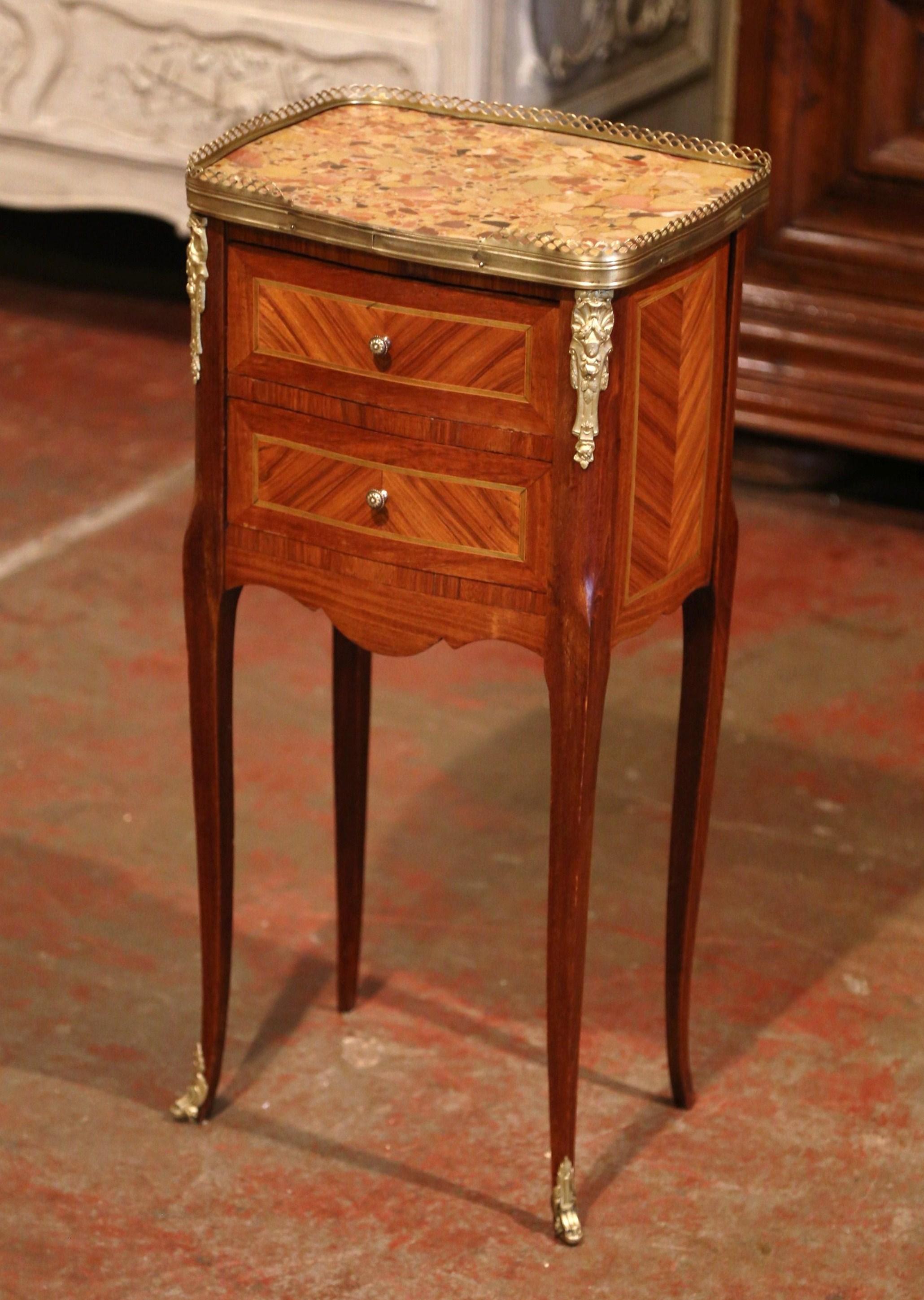 Crafted in France circa 1890, this elegant antique chest sits on cabriole legs decorated with bronze caps feet over a scalloped apron. The petite Louis XV style commode features two drawers across the front decorated with marquetry inlay work and