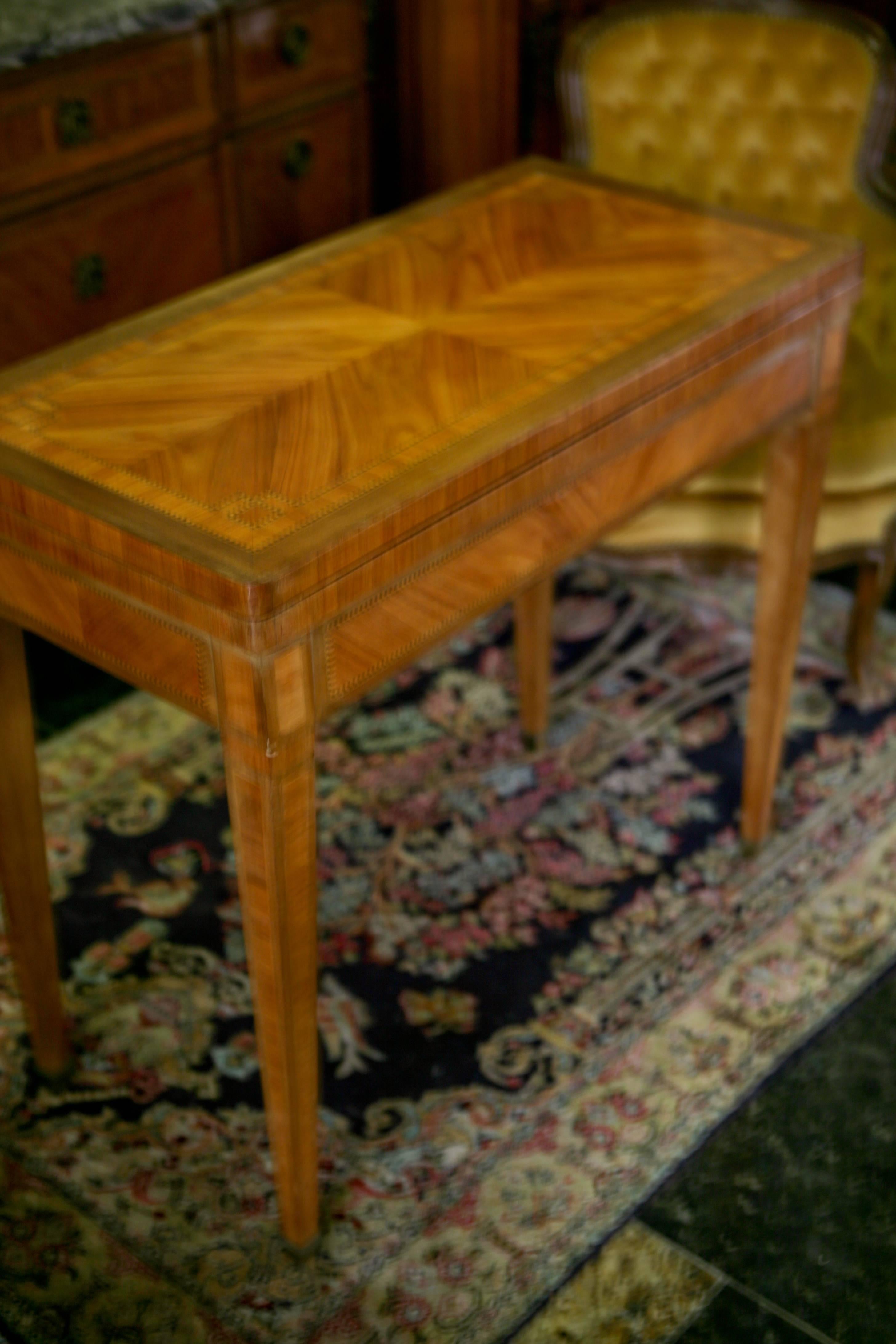 Une table à cartes en marqueterie française de bonne qualité. Le couvercle tourne et s'ouvre pour révéler une surface de jeu de cartes recouverte de tapis. Il repose sur des pieds coniques carrés incrustés,
France, datant d'environ 1800.