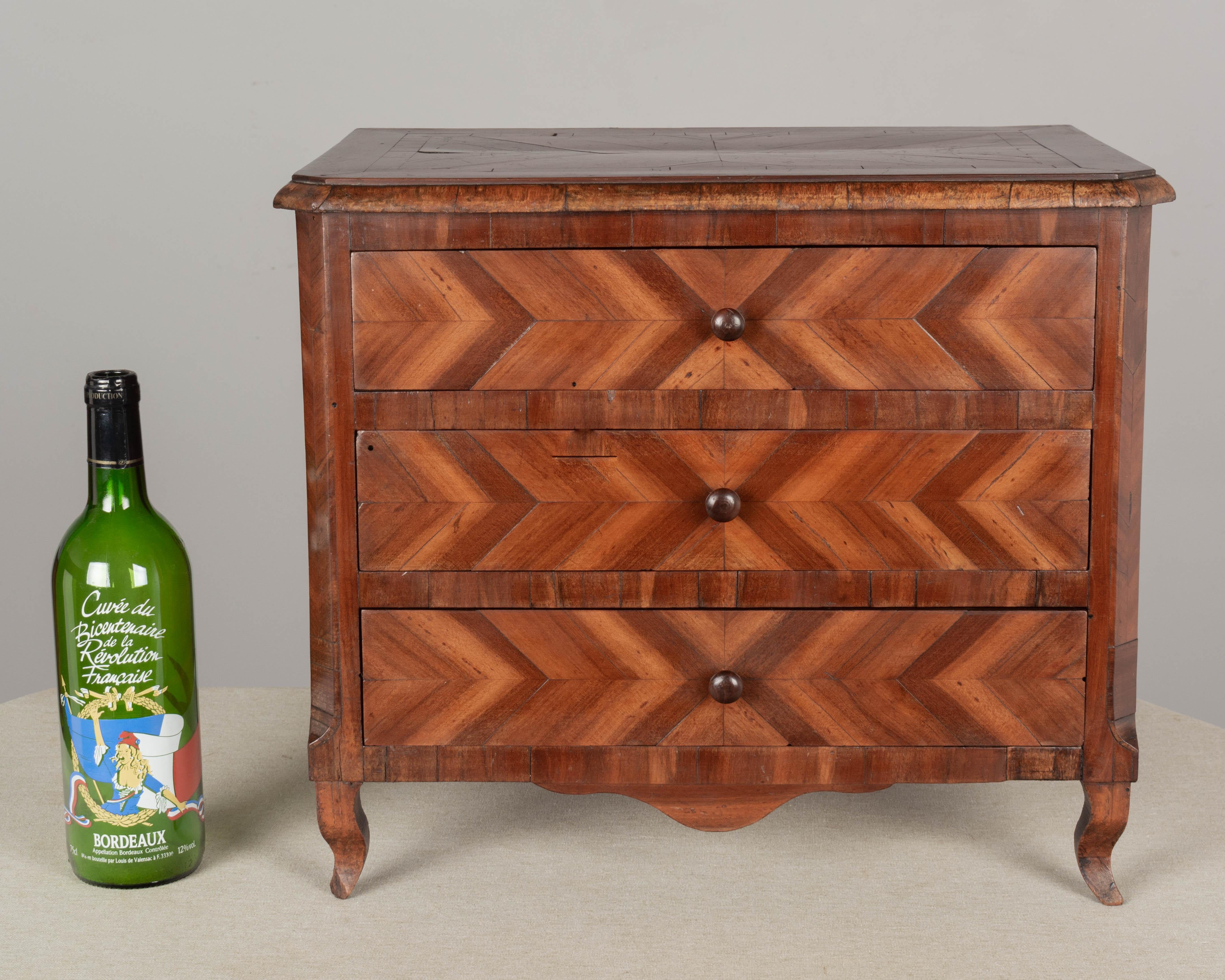 An early 19th century French marquetry commode de maitrise, or miniature sample commode. Made veneer of mahogany with pine and beech as a secondary woods. Three dovetailed drawers with herringbone patterned front and small turned knobs. In good