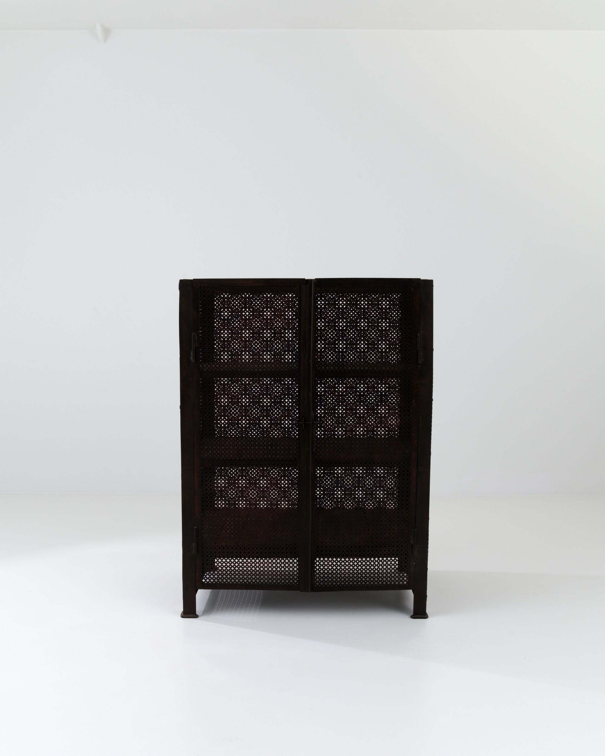 This antique metal cabinet marries a robust silhouette with delicate geometric patterning to create a unique early Industrial aesthetic. Built in France in the 1800s, the deep ferrous patina of the metal brings depth to the clean design. The frame
