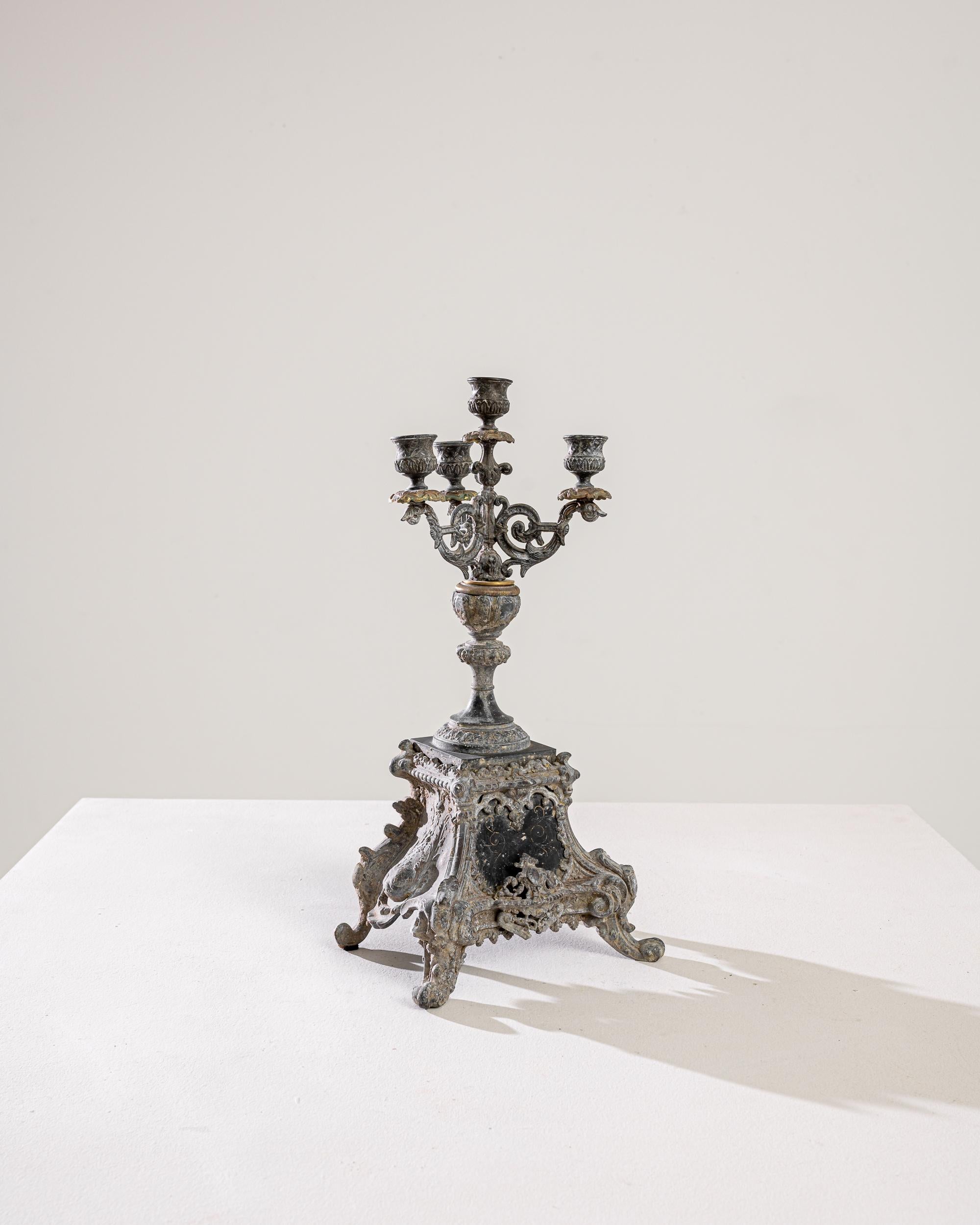 Lassen Sie sich vom Charme dieses französischen Metallleuchters aus dem 19. Jahrhundert verzaubern, einem Meisterwerk der Handwerkskunst, das die Zeit überdauert. Dieser Kerzenständer mit seinen kunstvollen Motiven auf dem Sockel strahlt einen Hauch