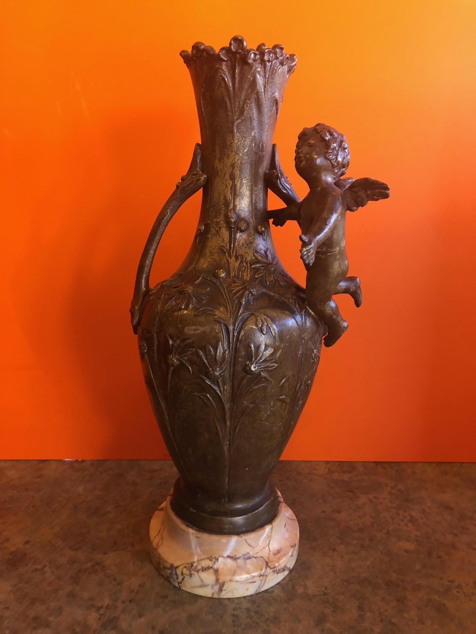 19th century French metal cupid vase, circa 1890s. The piece is in good vintage condition and sits on a round marble base.