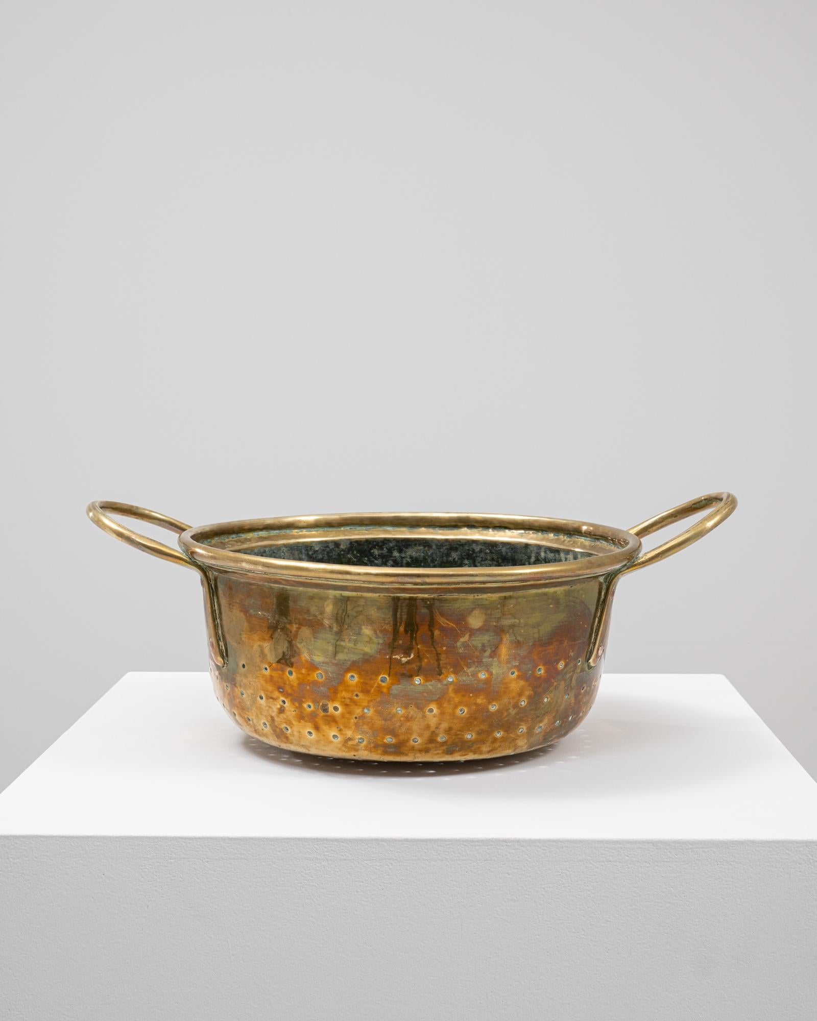 This 19th-century French metal ice bucket is crafted from hand-hammered brass, showcasing the warm, reflective tones characteristic of antique French metalwork. Its rounded form and wide rim are complemented by elegantly arched side handles,