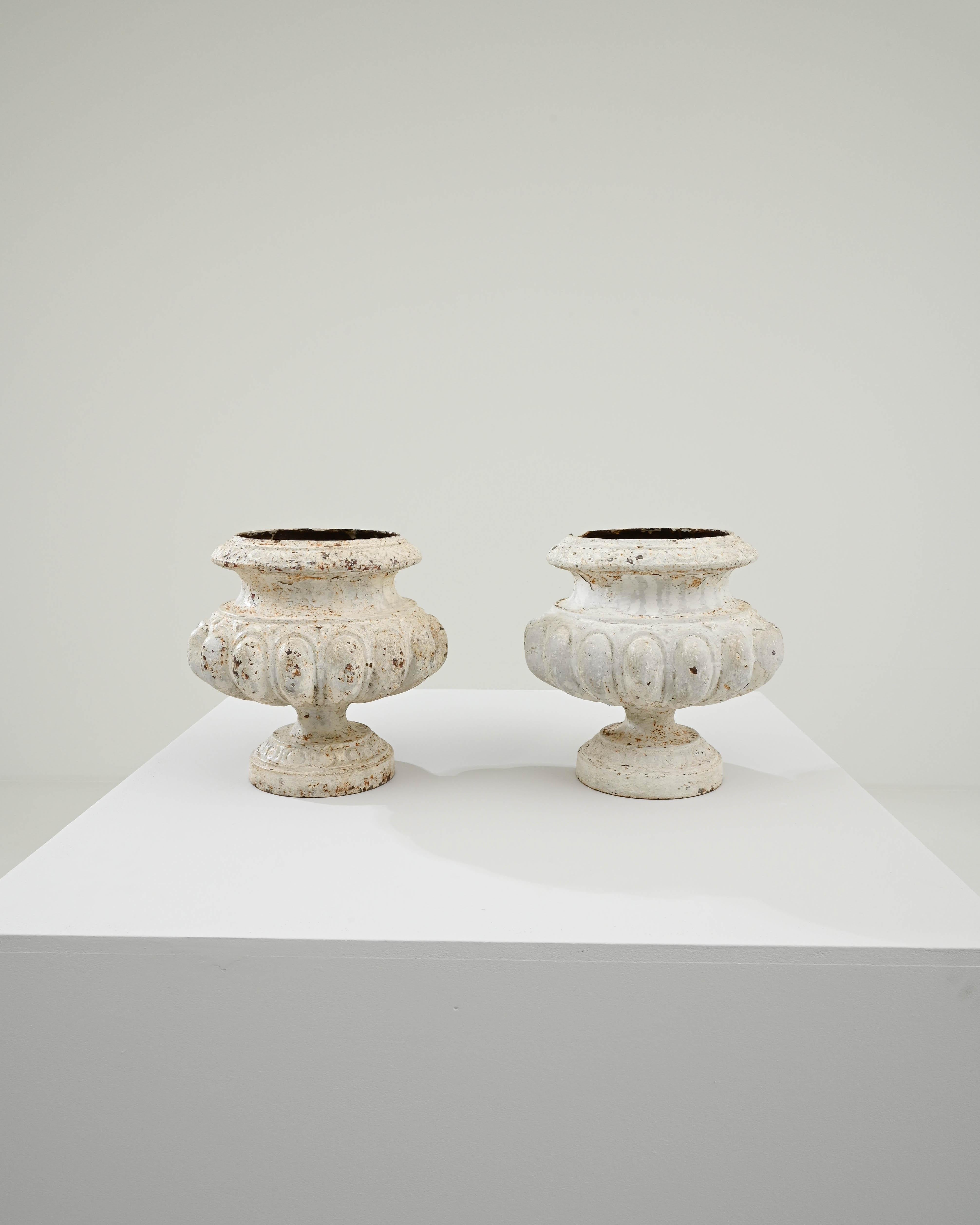A pair of cast-iron planters created in 19th century France by Alfred Corneau. Elegantly shaped and tapered, these classical planters impart a sense of classical beauty and a timeless resilience. A sturdy circular base tapers to a point to undergird