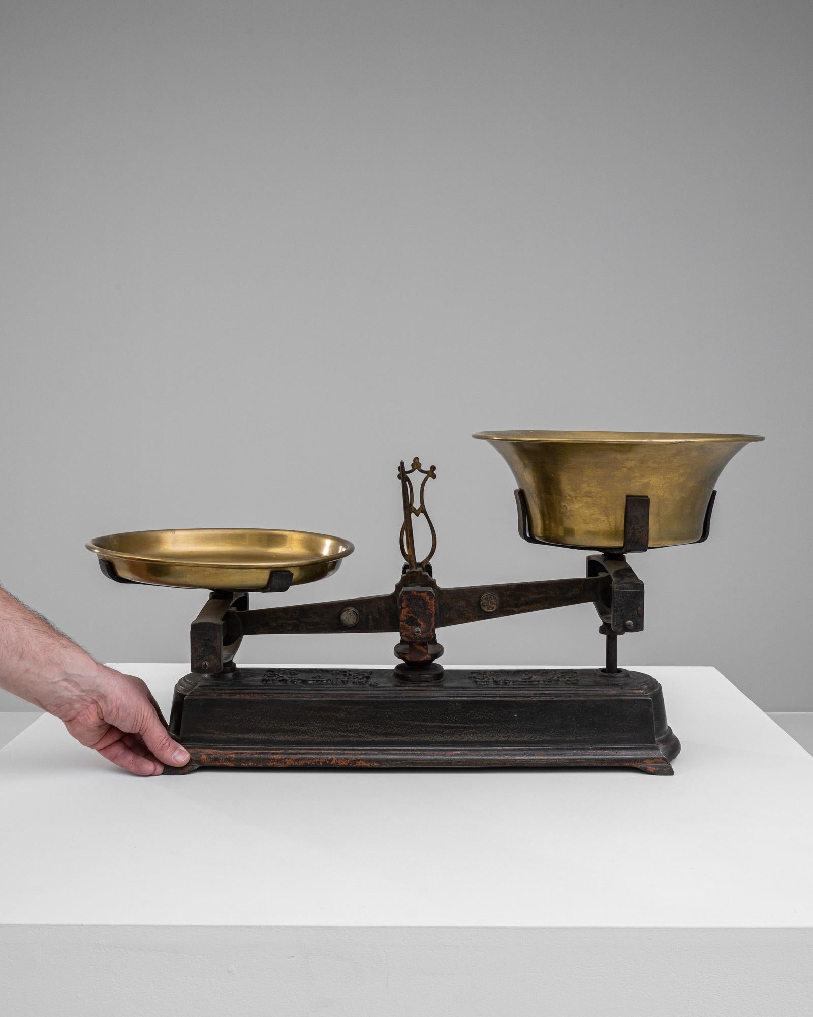 This 19th Century French Metal Scale is a splendid example of historical craftsmanship and decorative art. It features a sturdy iron base with elegant scrollwork detailing and the rich patina of age, indicating its long-standing service and