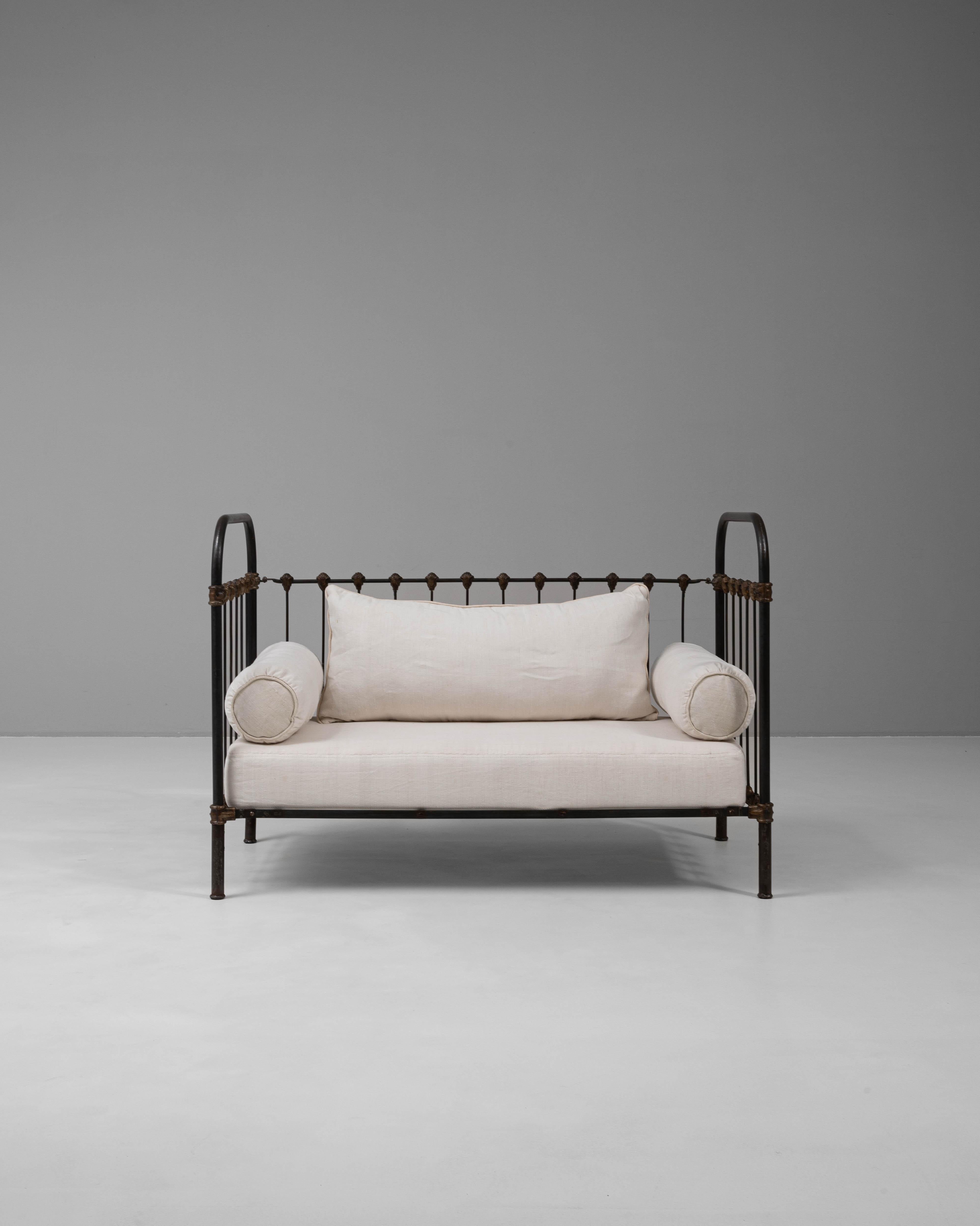 This 19th-century French daybed showcases a harmonious blend of rustic elegance and timeless craftsmanship. Constructed with a sturdy metal frame, its intricate detailing and patina add vintage charm, while the soft upholstered cushions provide
