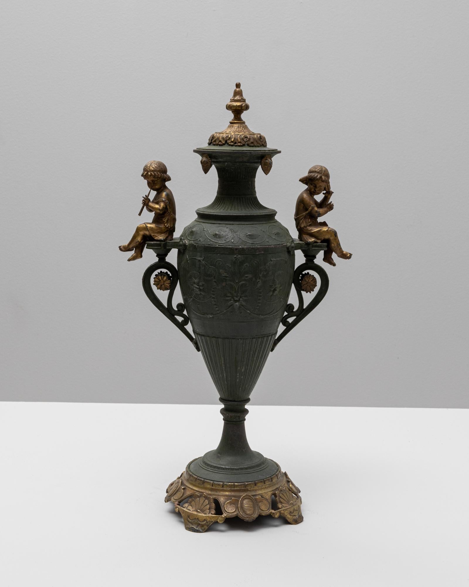 Questa squisita urna francese del XIX secolo riflette magnificamente l'arte romantica dell'epoca, grazie alla sua lavorazione in metallo finemente fuso con dettagli patinati in bronzo. Due figure in bronzo scolpite di bambini siedono con grazia