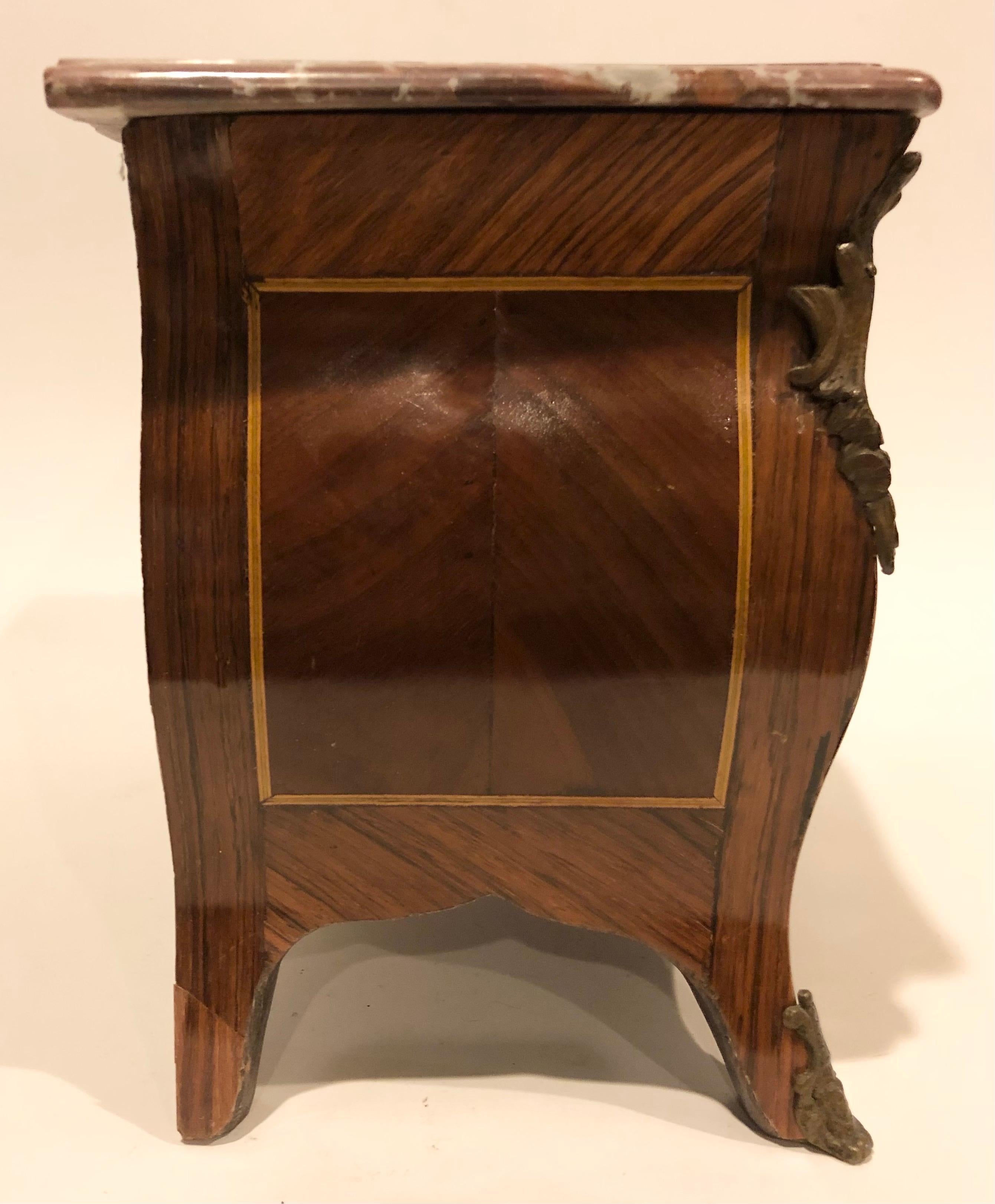 19th century French shaped miniature commode with wood inlays, bronze foliate accents and jasper red marble top. No key.