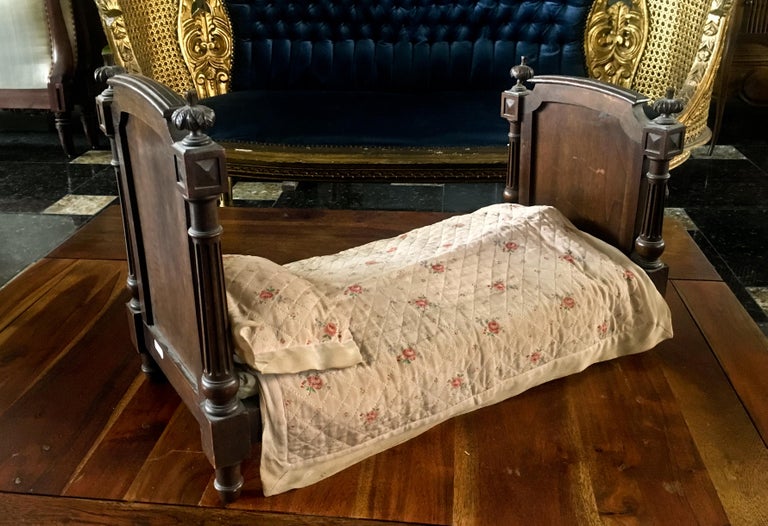 Natural molded walnut doll or dog daybed with splined columns topped with frets in Louis XVI style.
France, late 19th century
Measures: 36 x 55 x 27 cm.