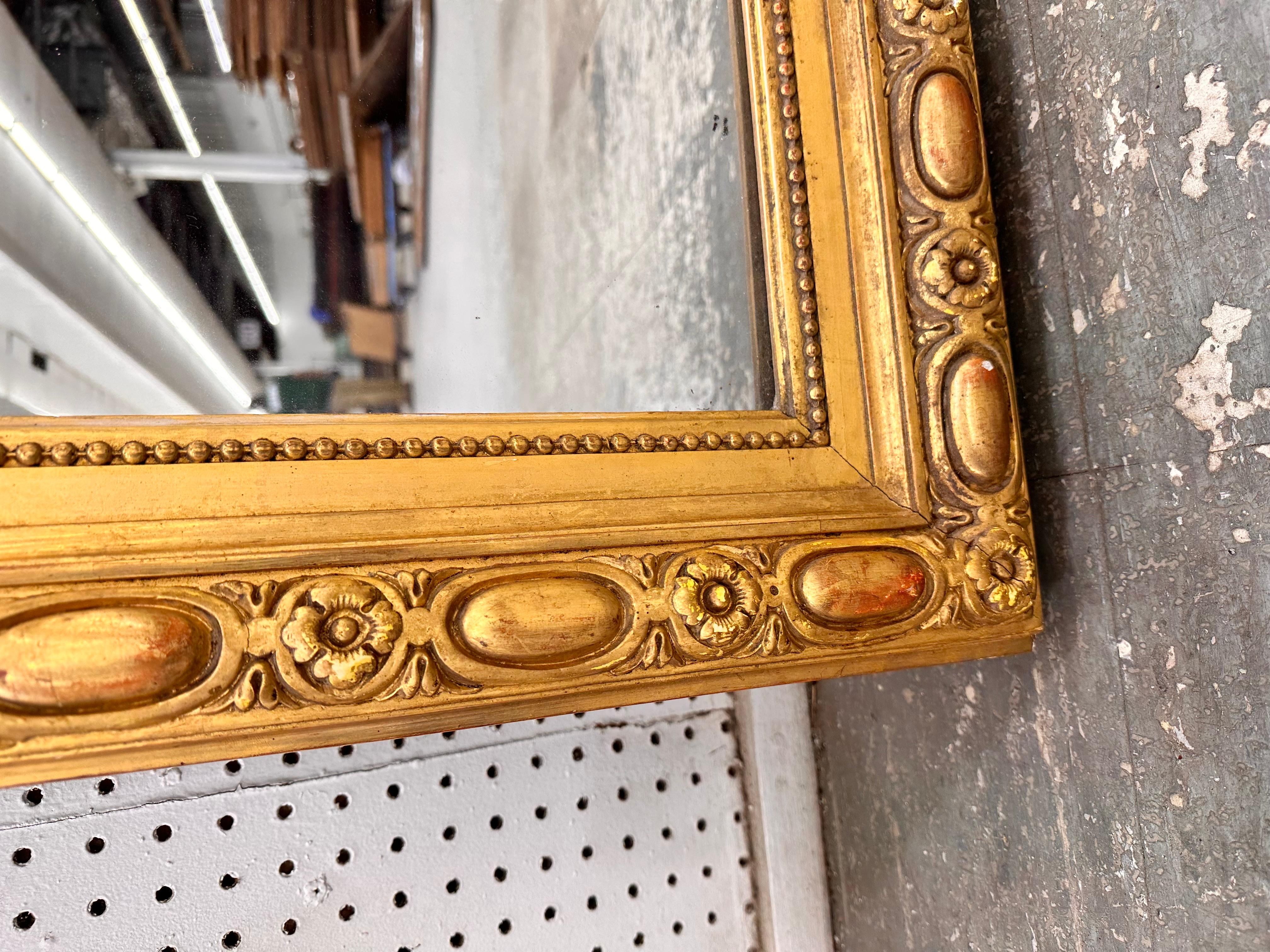 This 19th Century French mirror is top of its class! With its stunning gilded adornments such as its hand carved edging, ornate cartouche, and oversized silhouette, this mirror is bound to make a grand impression in any space. It has all of its