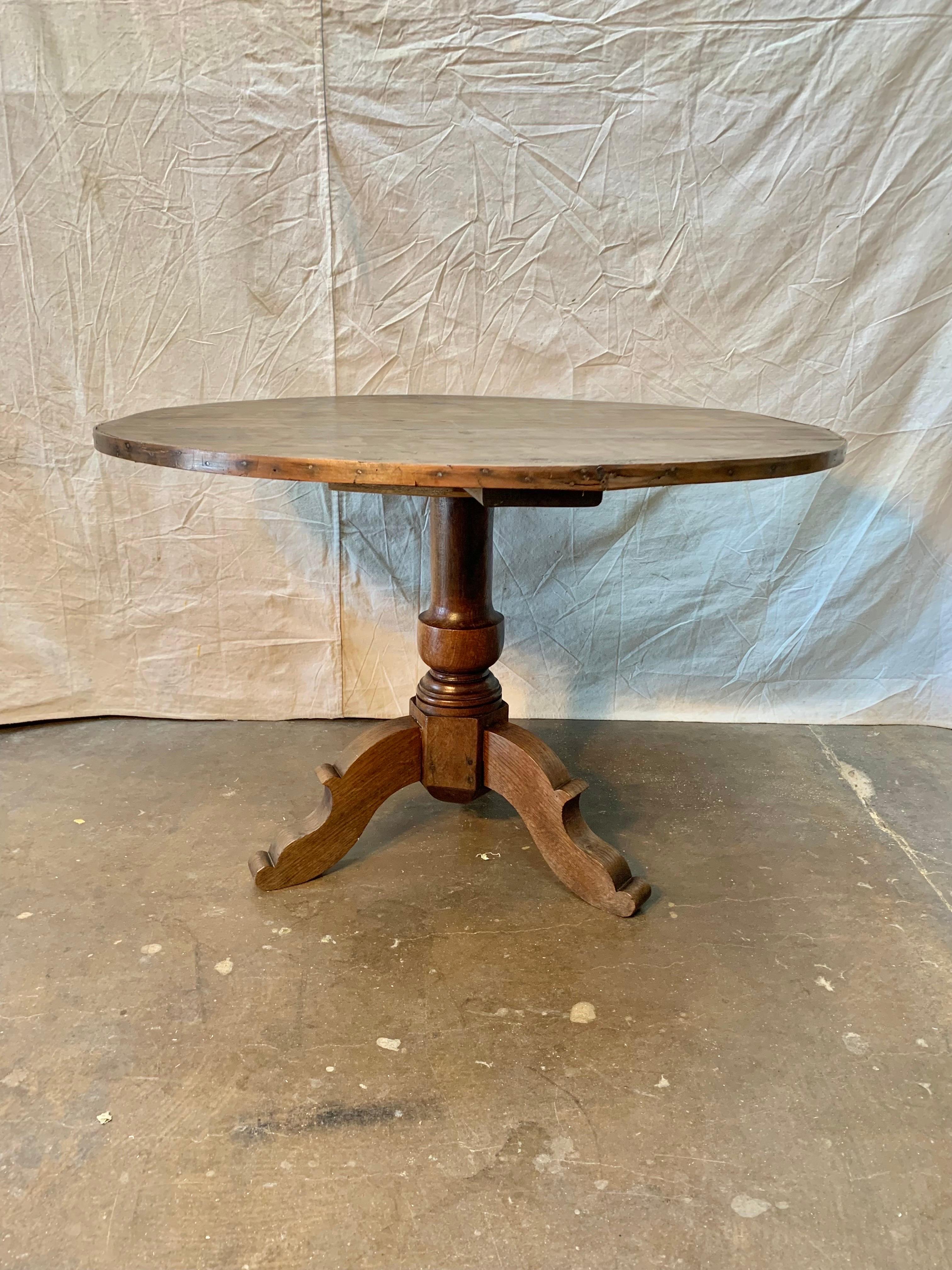 Found in France this 19th Century French Mixed Wood Center Table features a banded pine top raised on a walnut turned baluster support on a tripod base with three carved legs. The simplicity and size of the table lends it to be used as a center hall