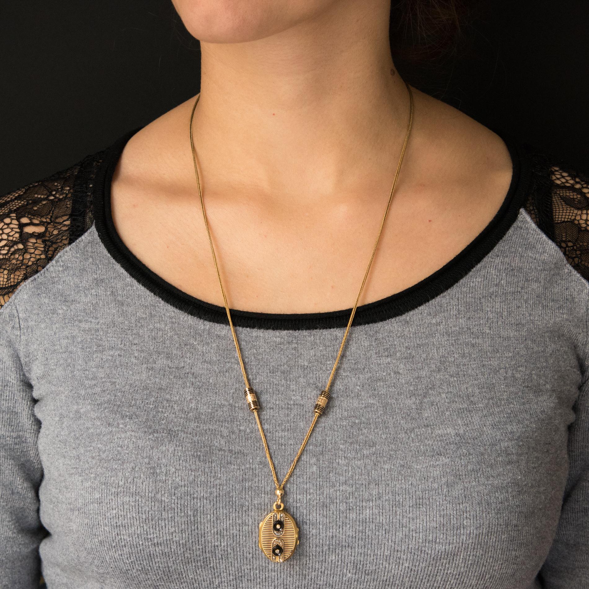 Pendant and its chain in 18 karats yellow gold, eagle's head hallmark.
This splendid antique necklace is composed of a column mesh chain on which slide cylindrical enamelled runners of black and chiselled lines which abut on small rings. This