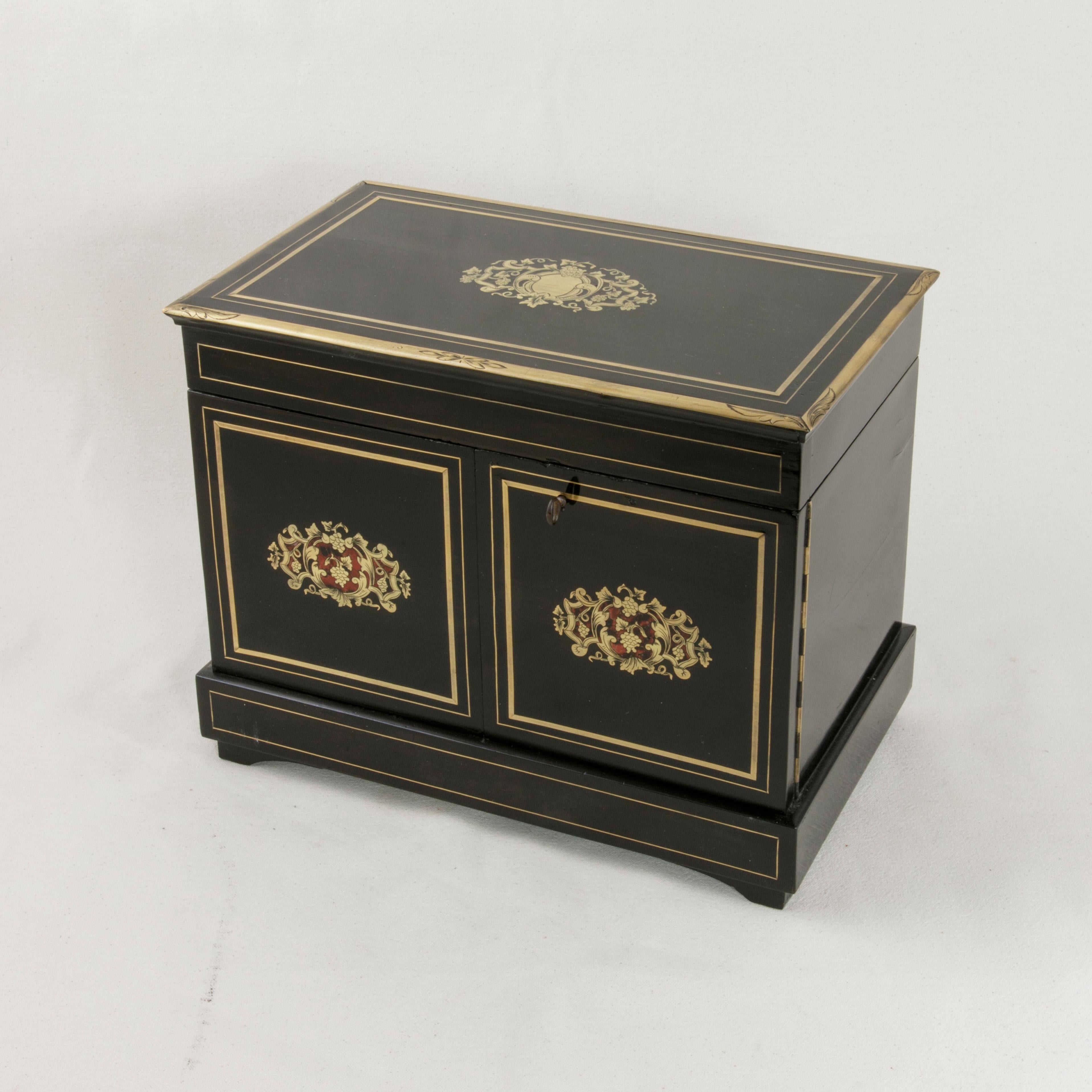 This mid-19th century French Napoleon III period black lacquer cave a liqueur (liqueur caddy) or tantalus features bronze and tortoiseshell inlaid cartouches on the lid and doors. Additional bronze banding trims the top and front panels of the box.