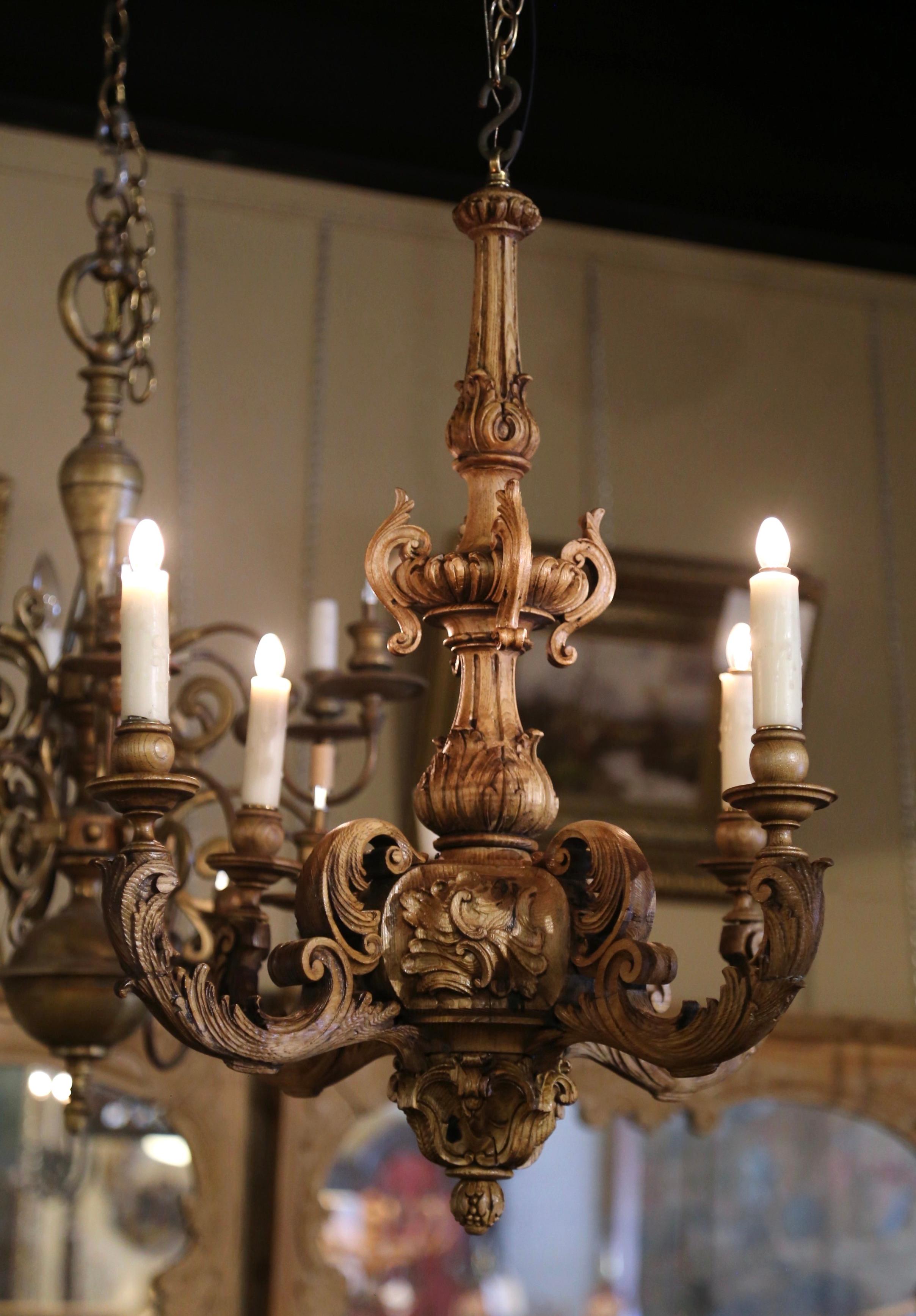 Decorate a dining room or a den with this elegant antique wooden chandelier. Crafted in France circa 1880, the light fixture is round in shape and features four arms of equal lengths around the thick intricately carved central stem; each curled arm